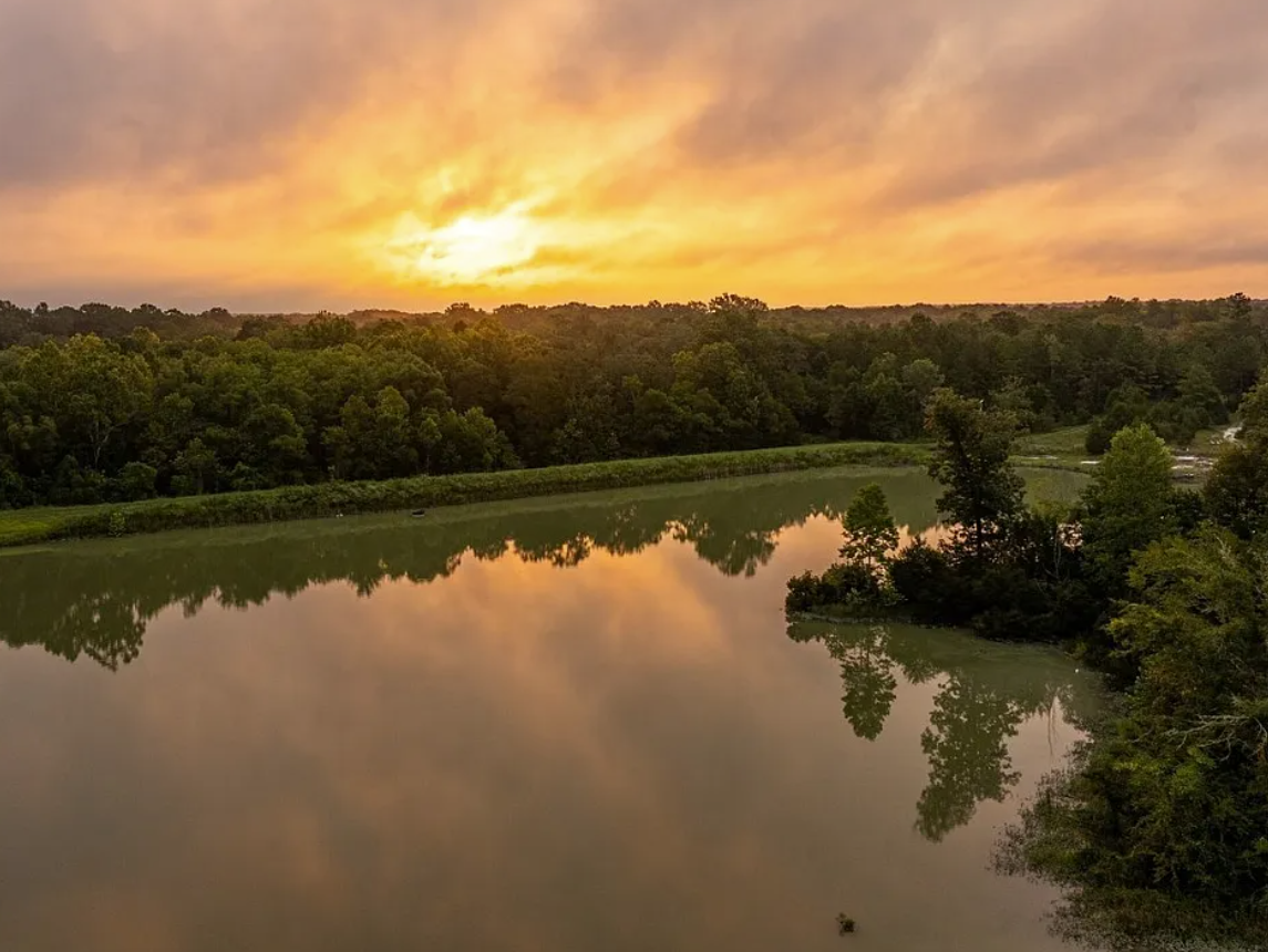 Sunset over a river reflecting the colorful sky and surrounding greenery.