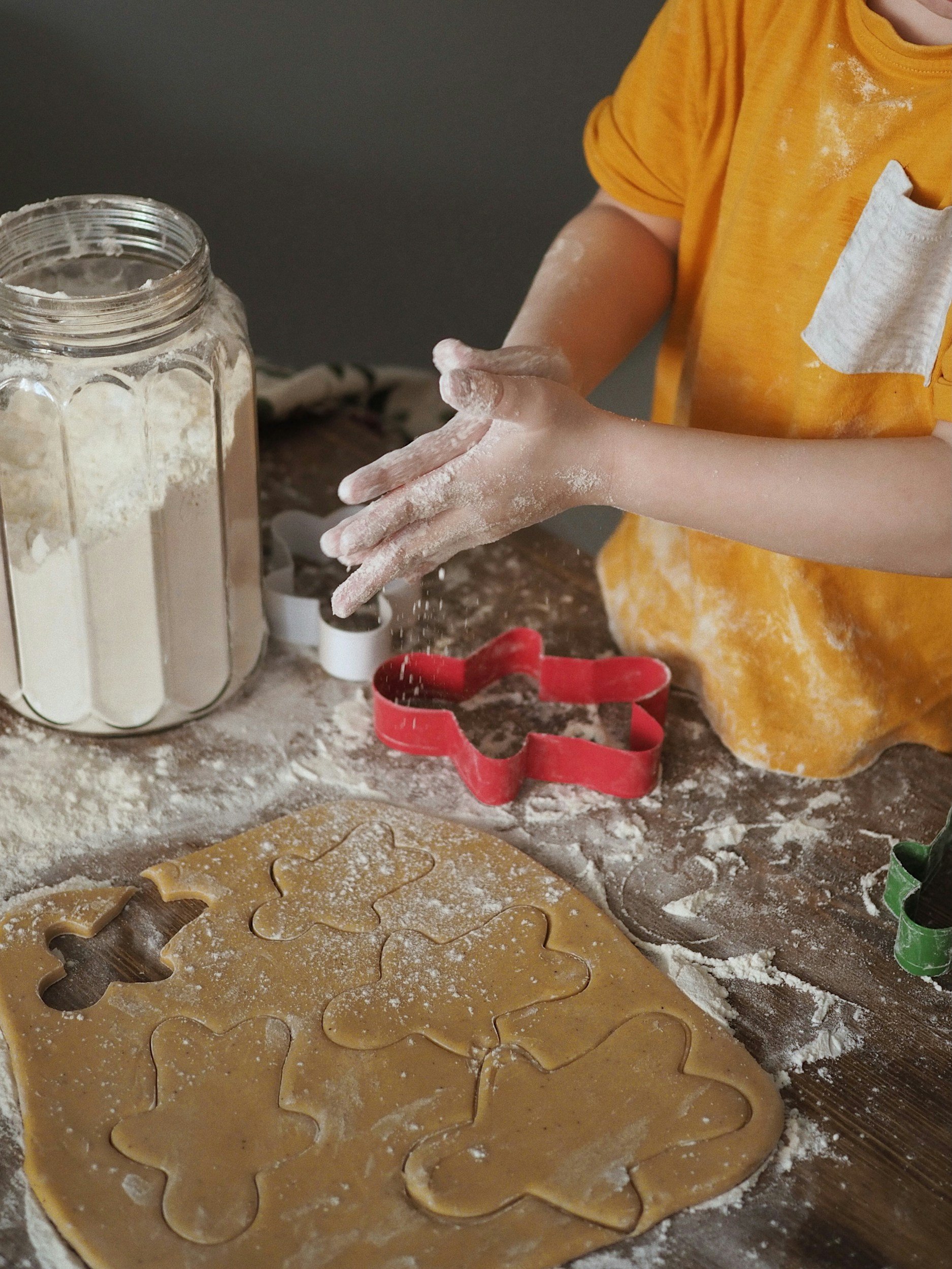 Child making cookies with cookie cutters during a hands-on baking activity.