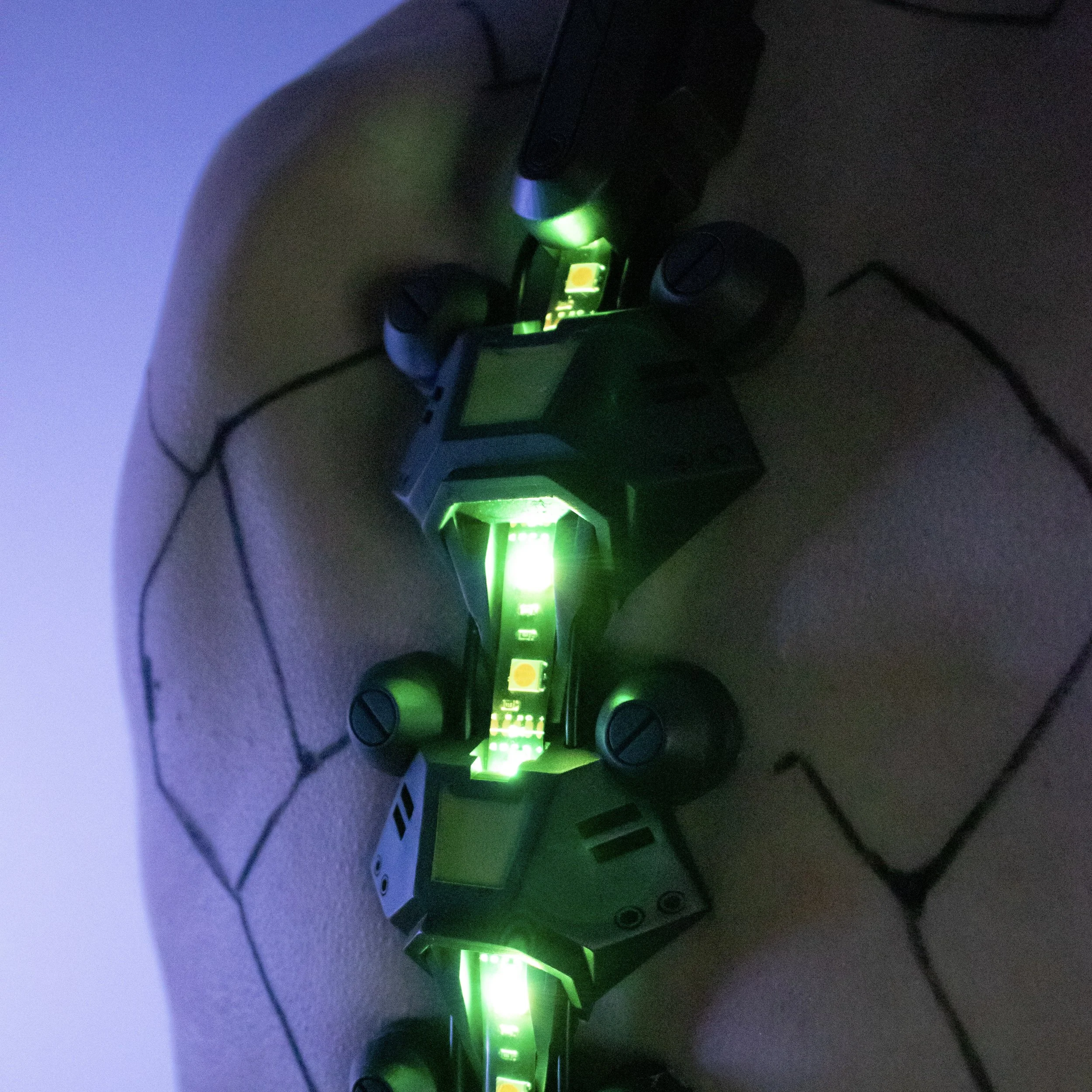 Two small robot-like devices with green LED lights are placed on a tan, stitched surface, possibly a cushion or seat.