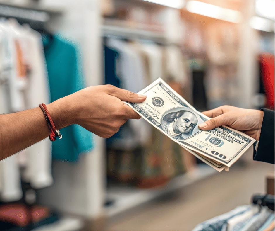 Person handing over cash to another person in a retail store.