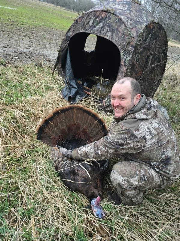 Michigan spring turkey hunter with eastern wild turkey and ground blind during a successful hunt.