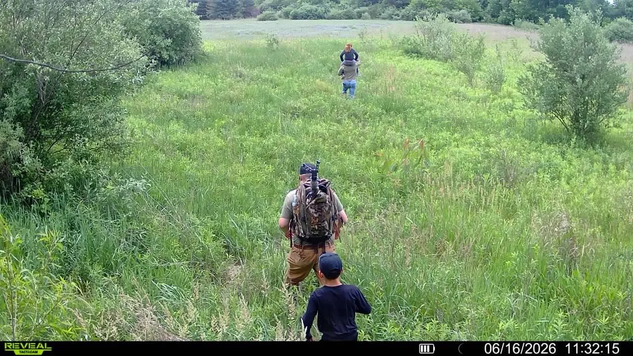 A small group walks across Michigan public land, illustrating outdoor education, scouting, and conservation.