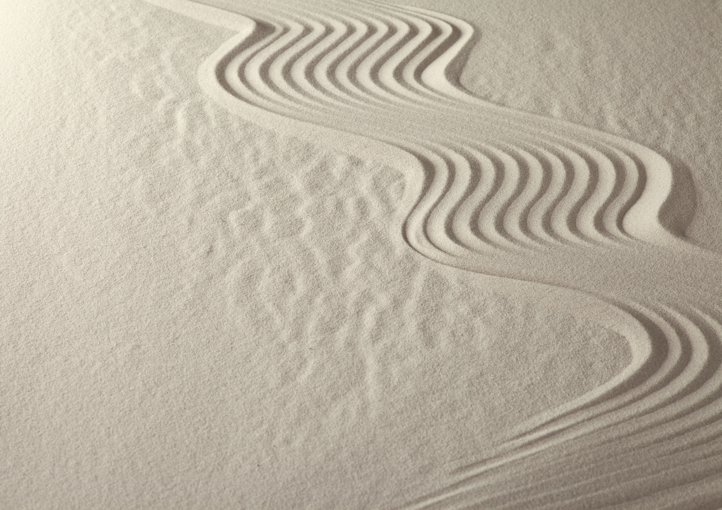 Close-up of sand with wind-created ripples and footprints.