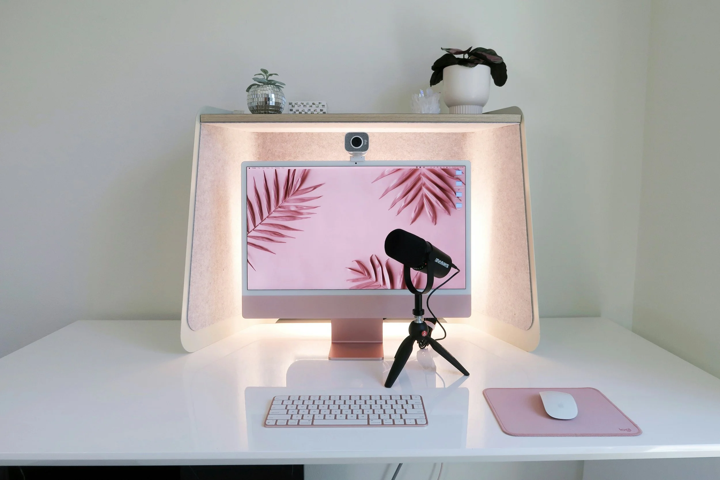 A pink iMac with pink accessories on a white desk perfect for content creation.