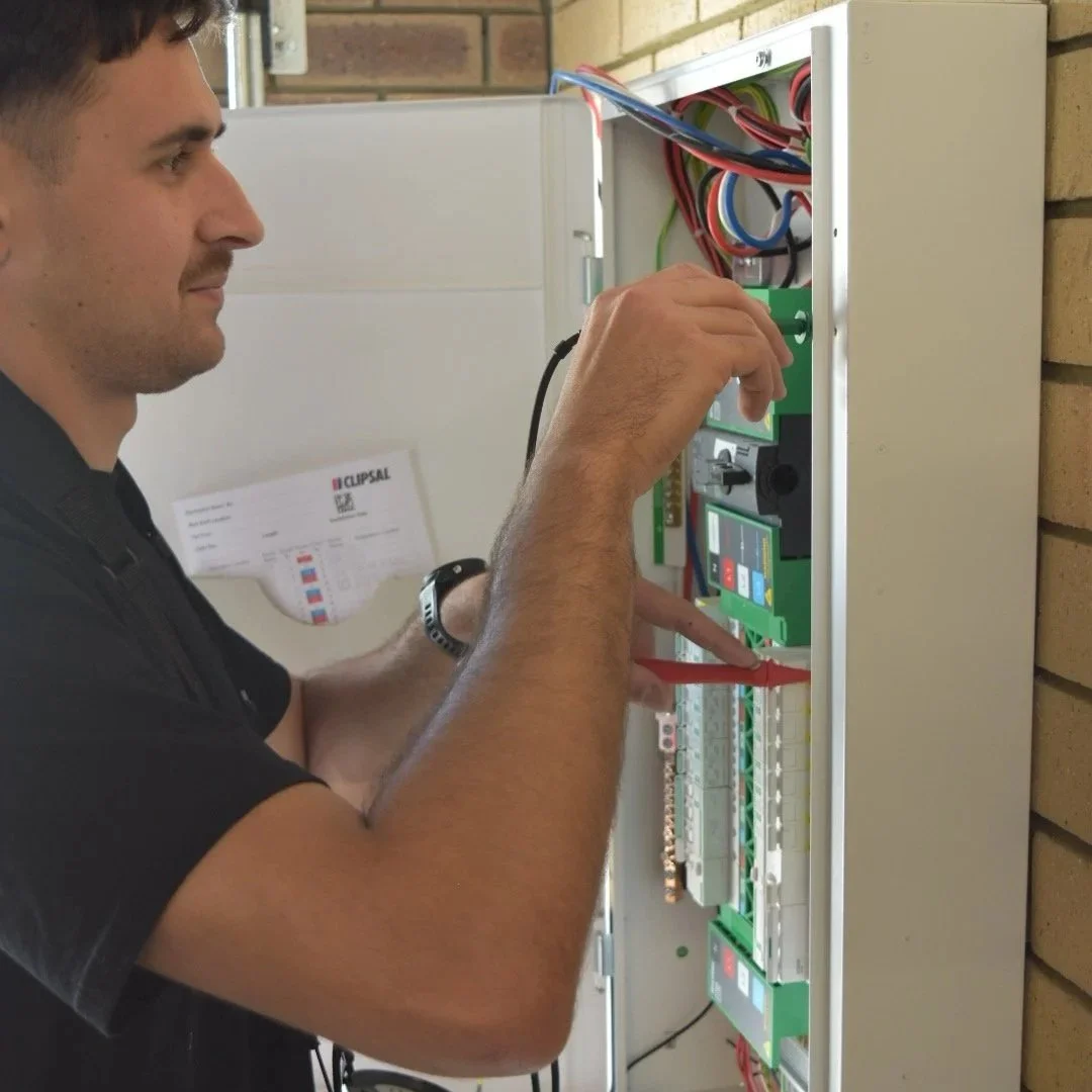 A man working on an electrical control panel, wiring and components.