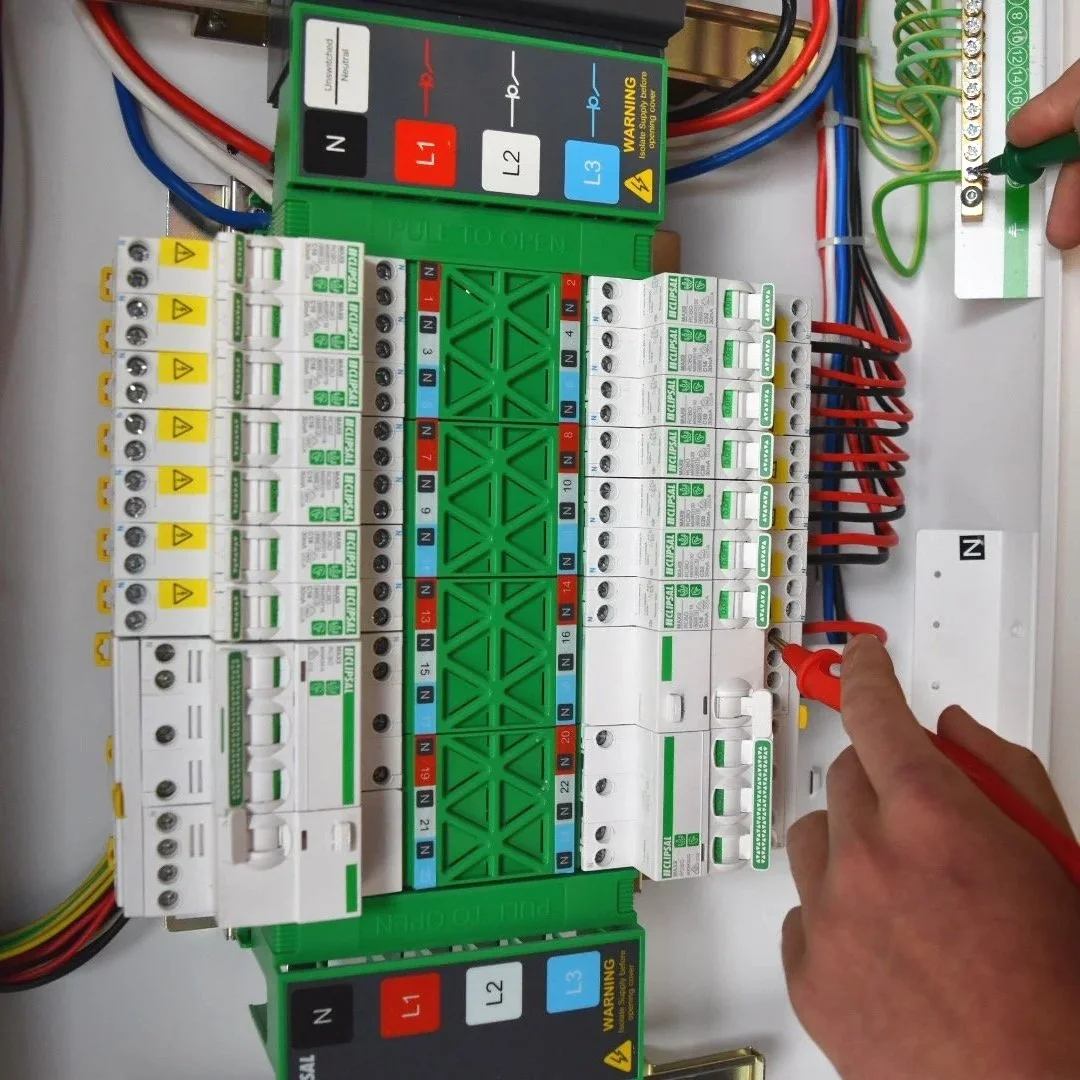 Electrical control panel with wiring and circuit breakers, person using a screwdriver to work on the panel.