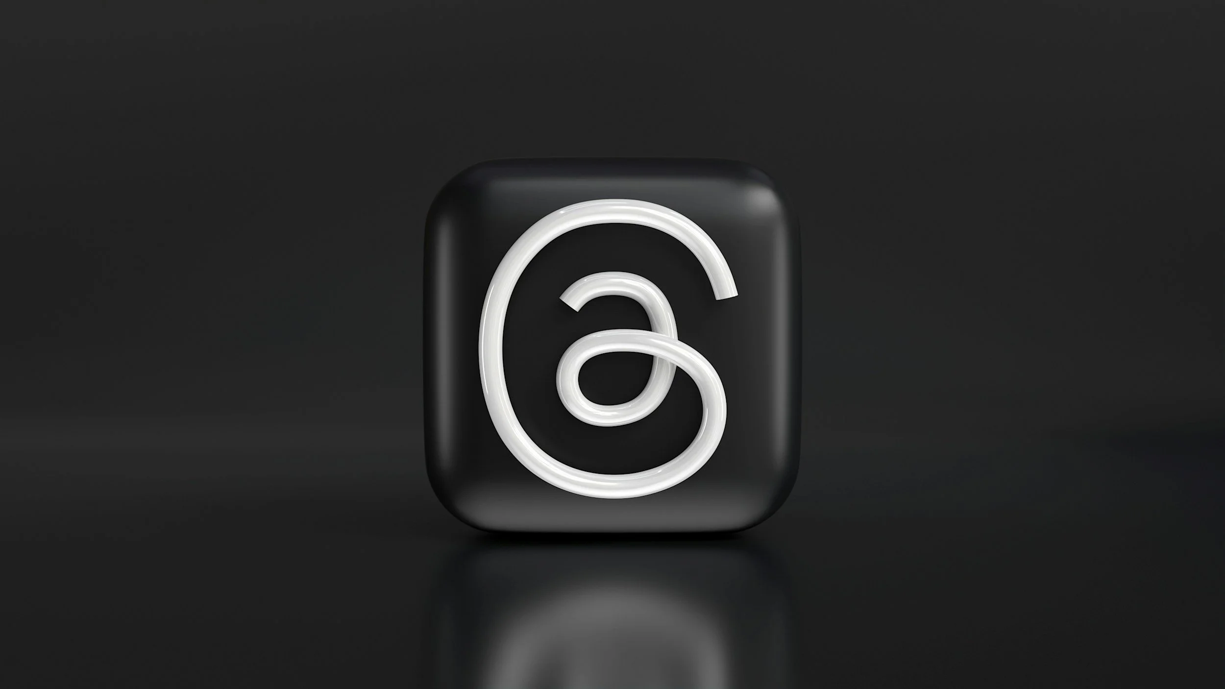 Neon sign of the Spotify logo in white on a black background.
