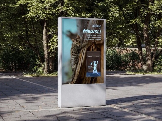Freestanding outdoor display with a cat on the graphic and surrounding trees in a park-like setting.