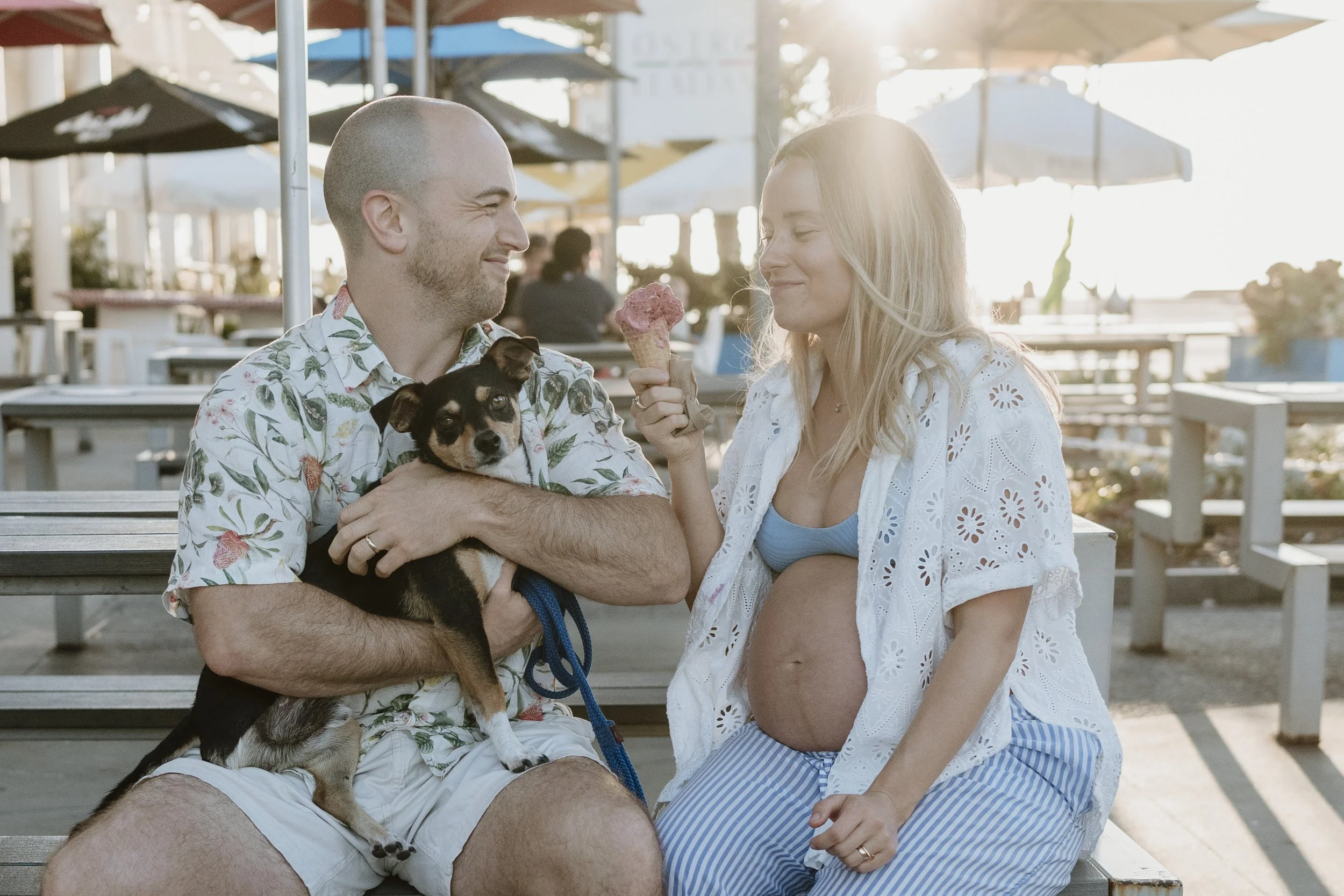 Candid moment between expecting parents and their dog during their outdoor maternity session