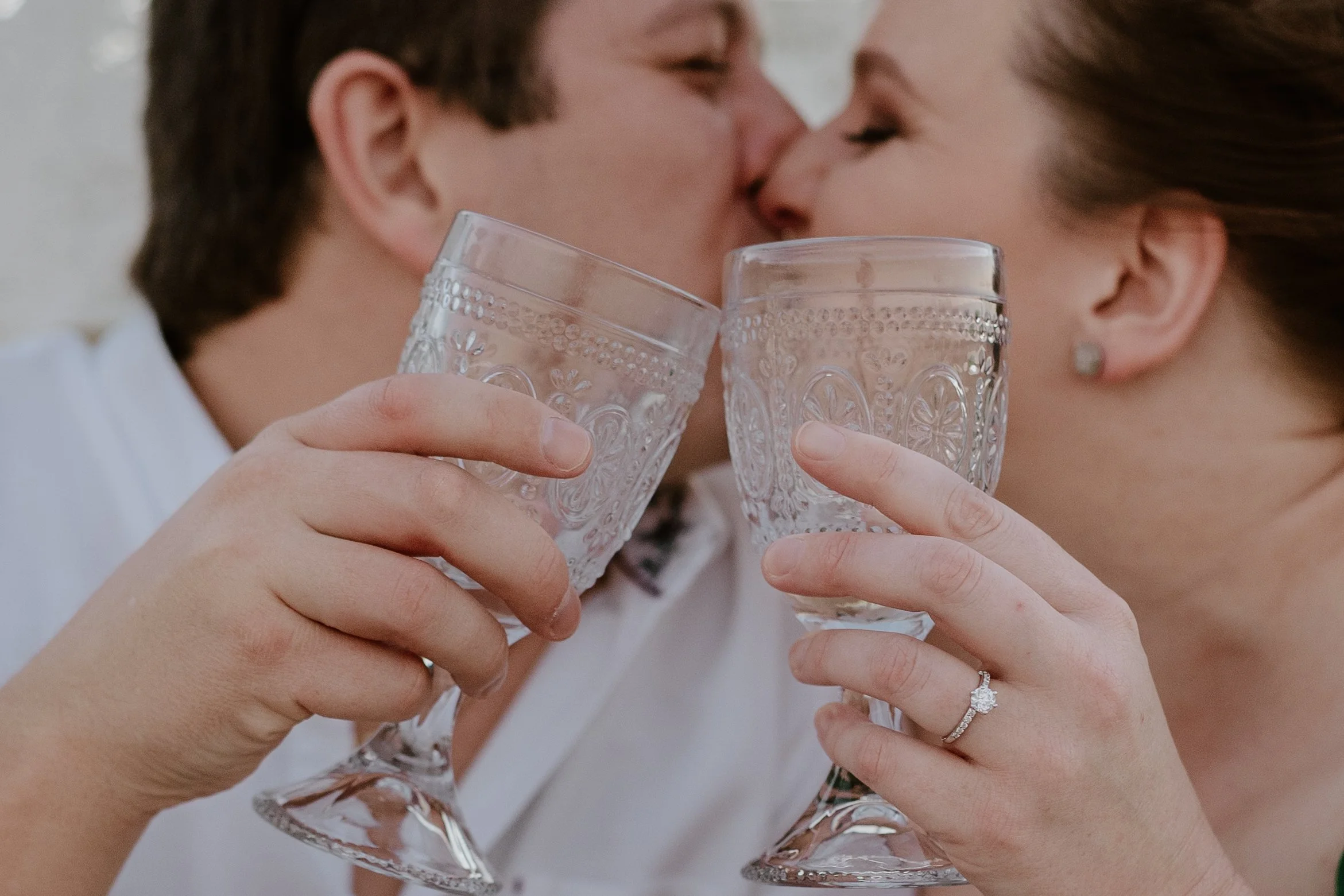 A candid moment as the newly engaged couple celebrate with a cheers and kiss