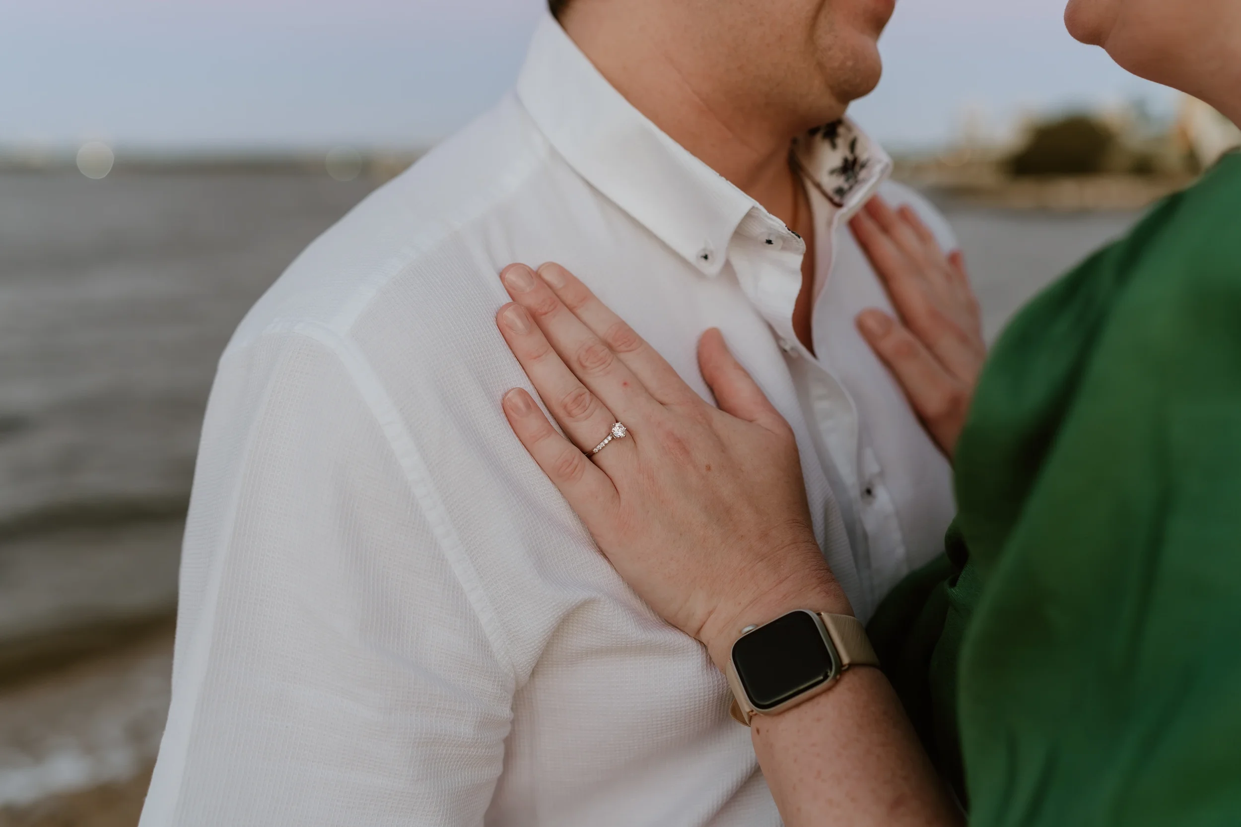 Close-up of Pauline's hands showing the engagement ring as the Swan River glistens in the background