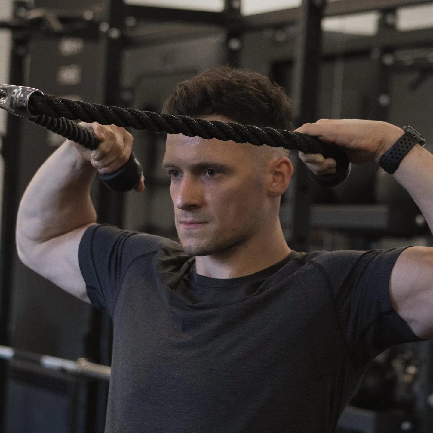 A man lifting a rope in a gym.