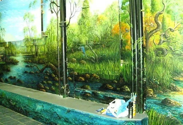 Colorful mural of a lush wetland scene with trees, water, and rocks, in an indoor space.