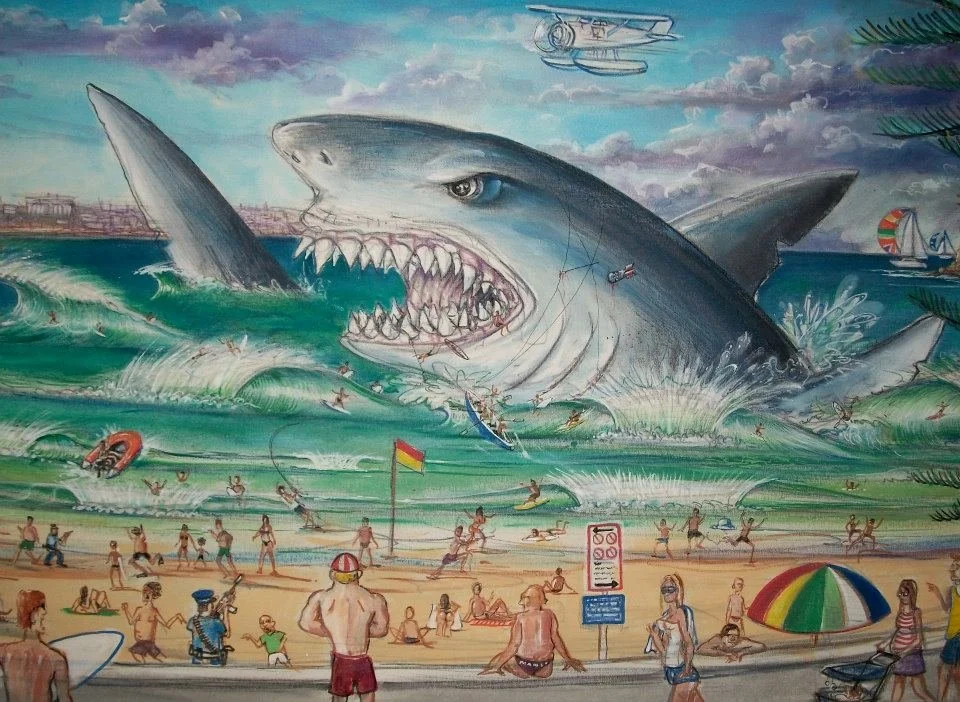 Famous beach scene mural depicting a giant attacking shark with beachgoers and surfers in the foreground.