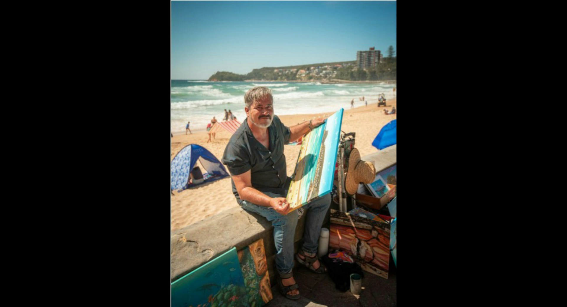 Mark Budd painting a mural on the Manly beachfront, creating whimsical coastal artwork
