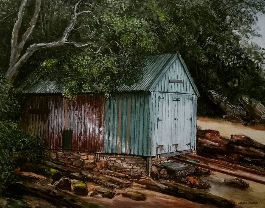 A rustic shed with metal siding in a natural landscape, surrounded by trees and rocks.