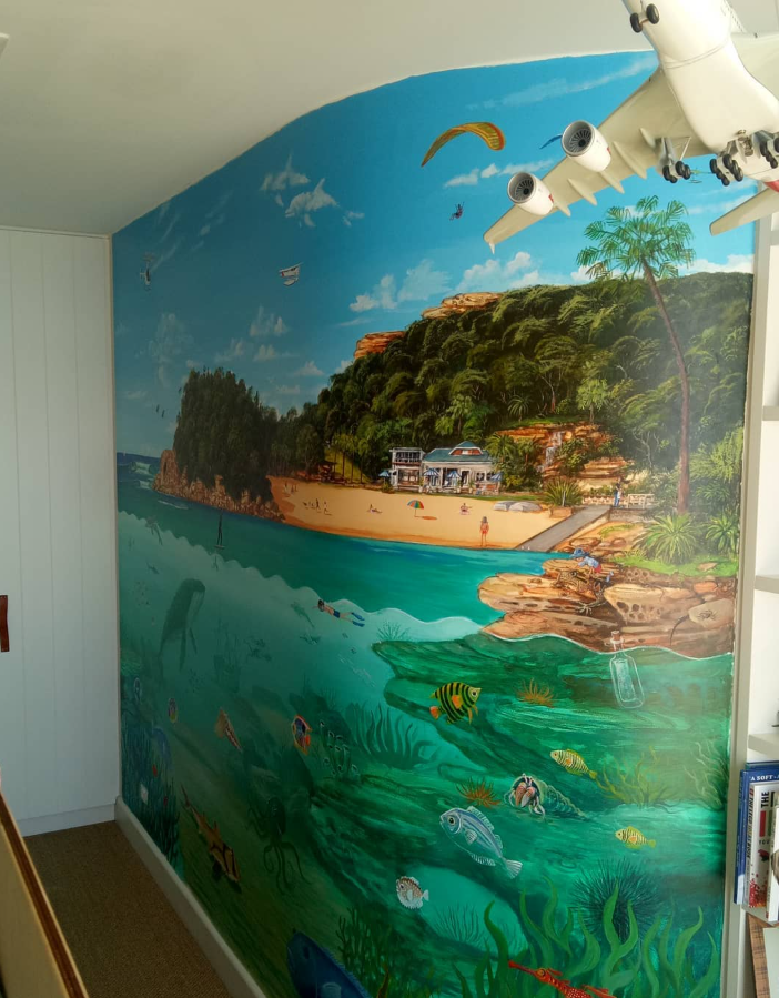 Colorful mural depicting a beach scene with the ocean, sandy shore, palm trees, houses, and fish underwater.