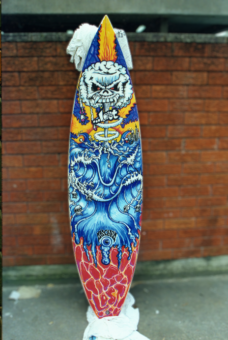 Colorful skateboard deck with a graphic of a skull with flames and a large wave design, set against a brick wall background.