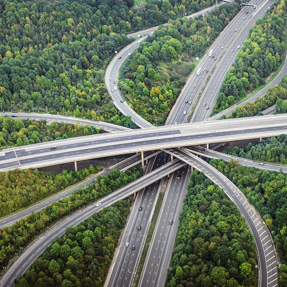 Aerial view of multiple highway overpasses and roads crossing over lush green forest.