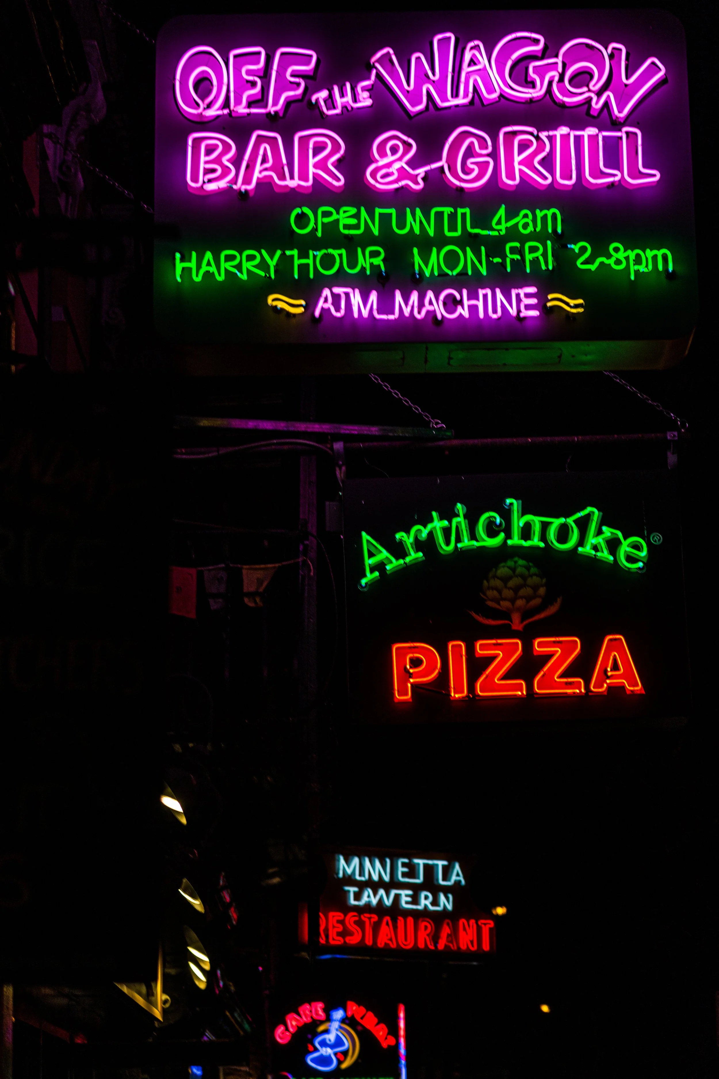Neon signs advertising QEF The Wagger Bar & Grill, Artichoke Pizza, Minetta Tavern, and a bar or night club.