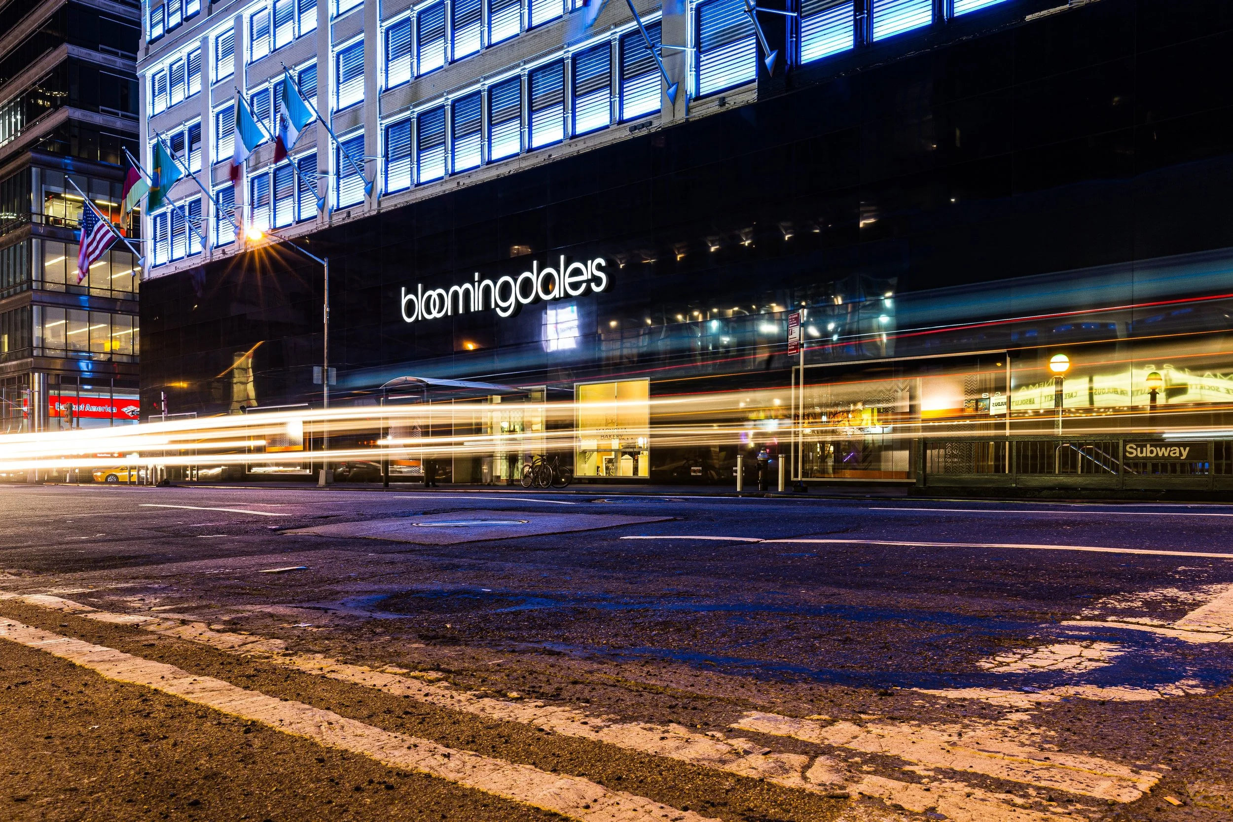 Night view of Bloomingdale's department store with motion blur of passing traffic in New York City.