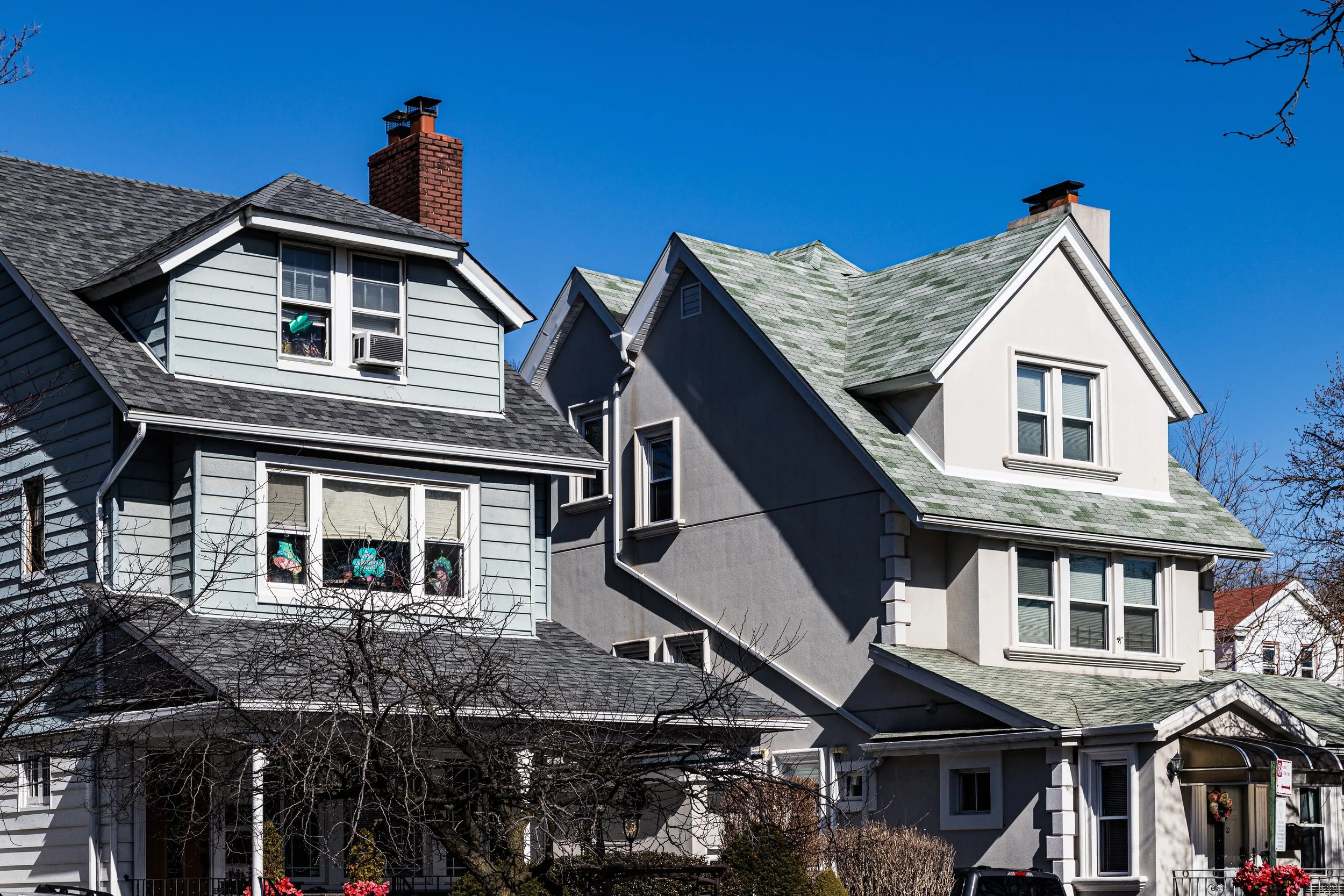 Multiple detached houses with gabled roofs under a clear blue sky.