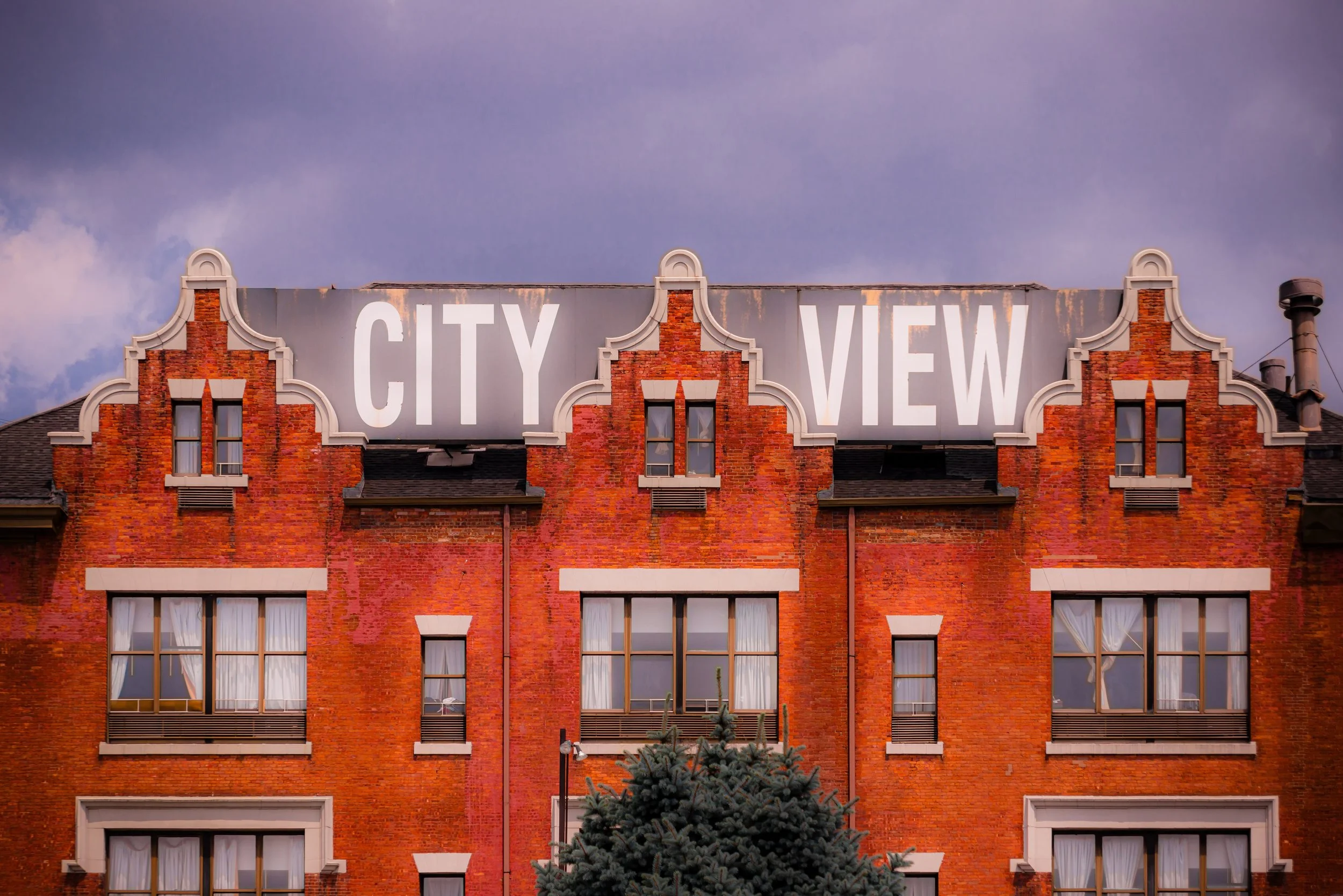 A brick building with a large sign on top that says 'CITY VIEW,' set against a cloudy sky.