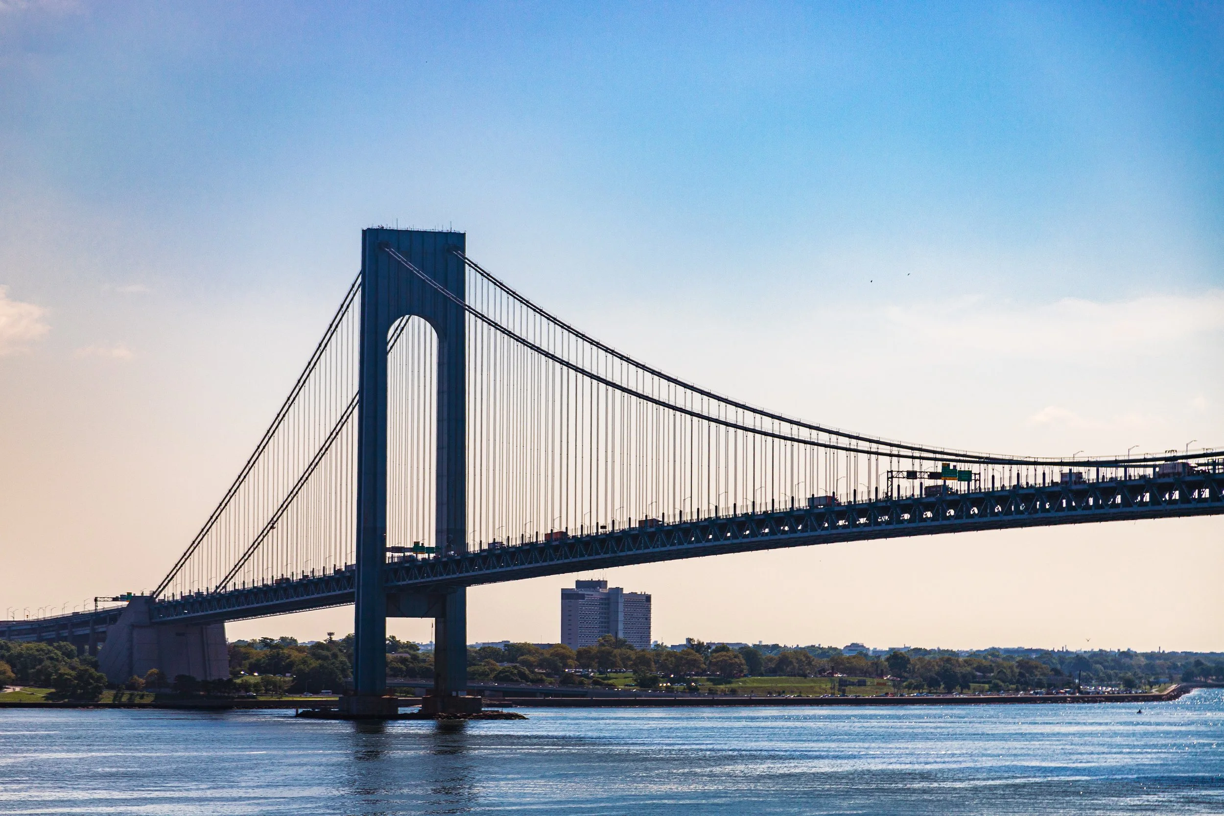 Photo of the George Washington Bridge spanning the water with a cityscape in the background under a clear blue sky.