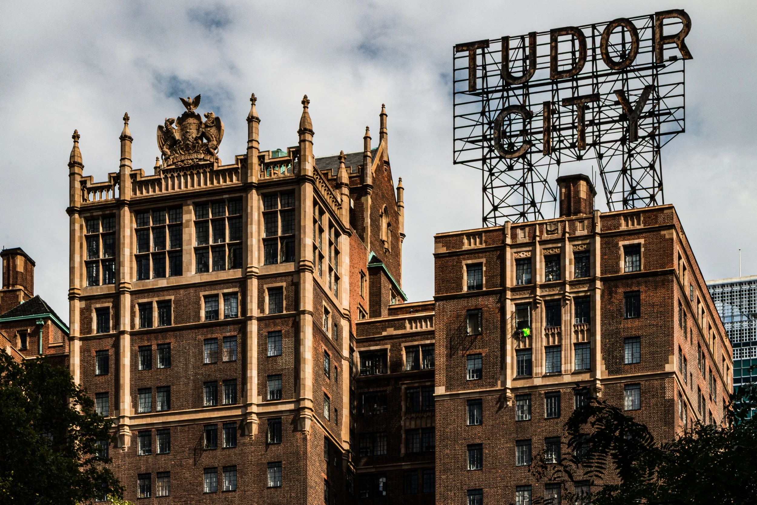Old brick buildings with a large metal sign that reads "Tudor City" on top.