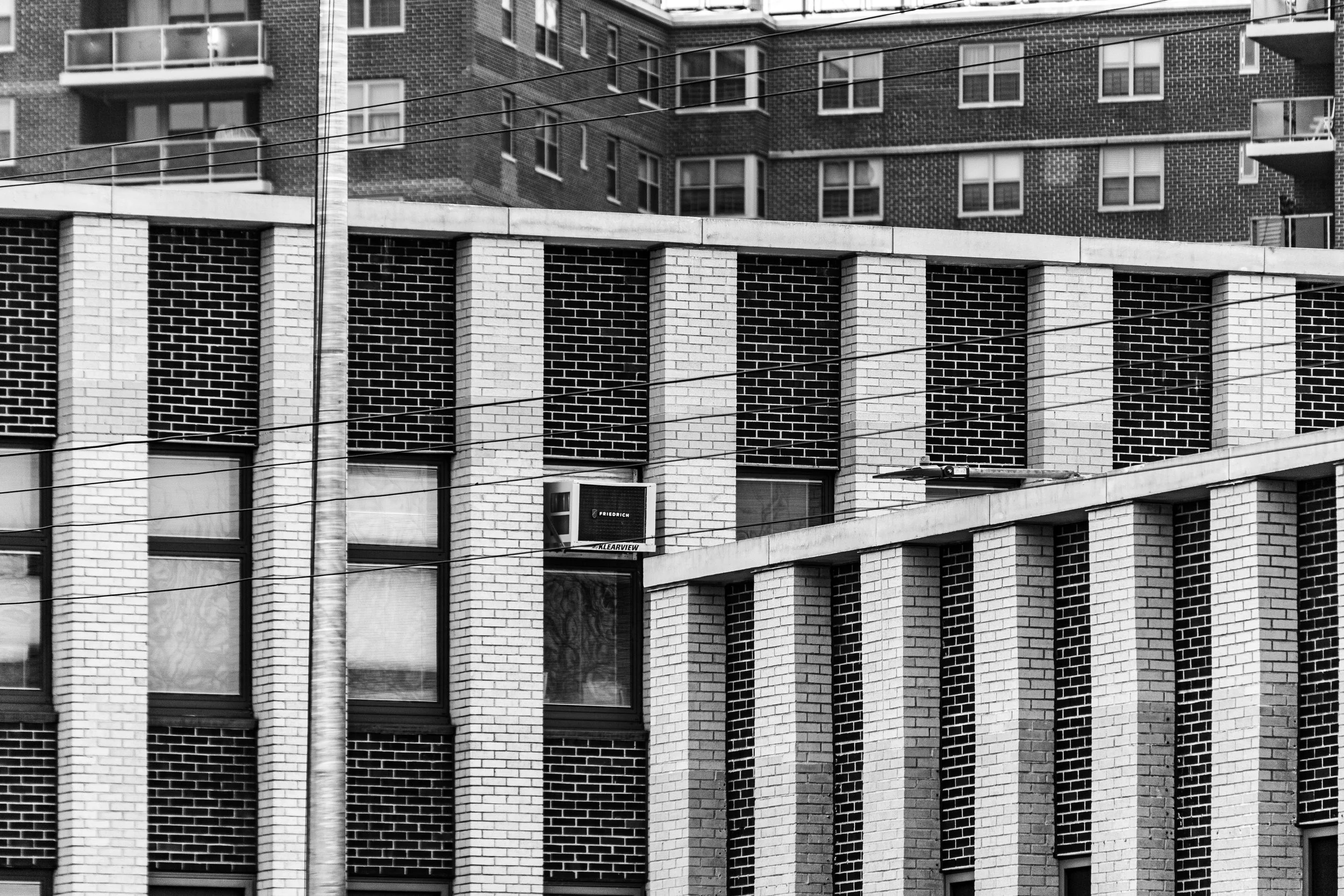 Black and white photo of a modern multi-story apartment building with large windows and brick and concrete exterior.