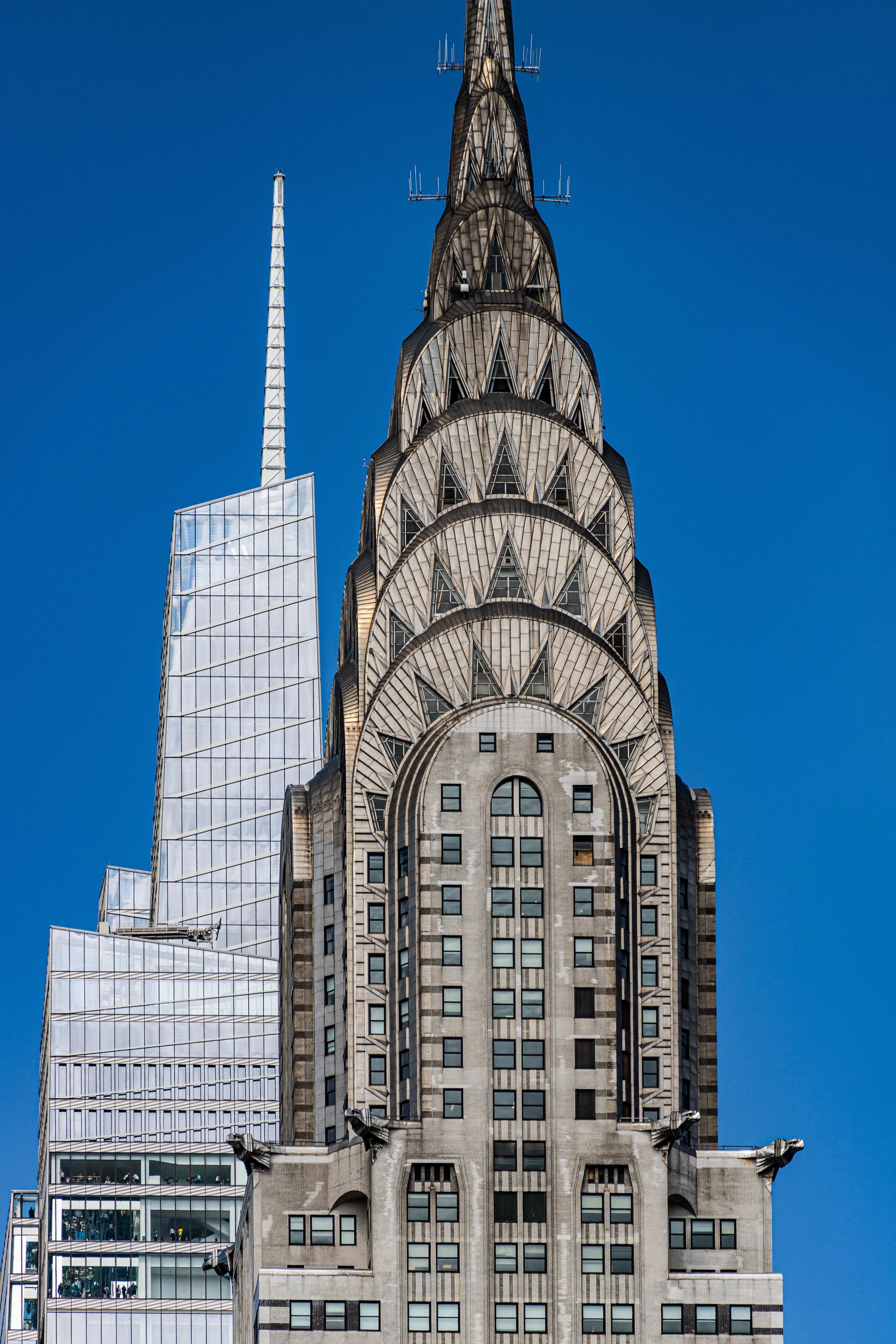 Close-up of the top of the Chrysler Building, an Art Deco skyscraper in New York City, against a bright blue sky.