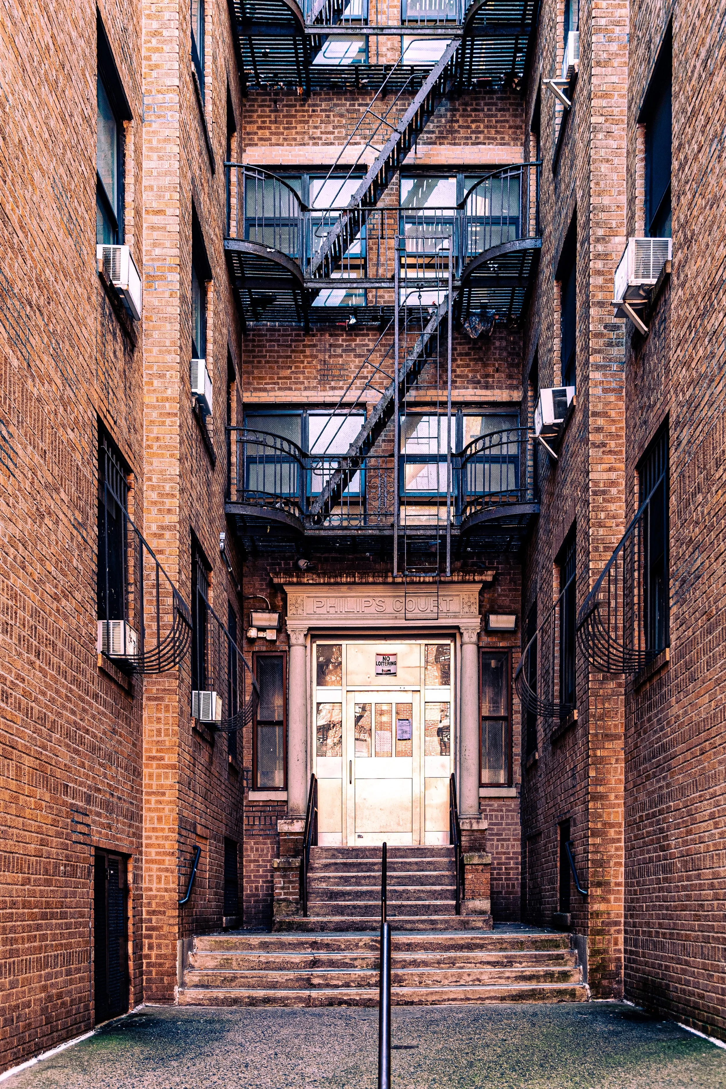 Brick apartment building entrance with stairs and fire escape.