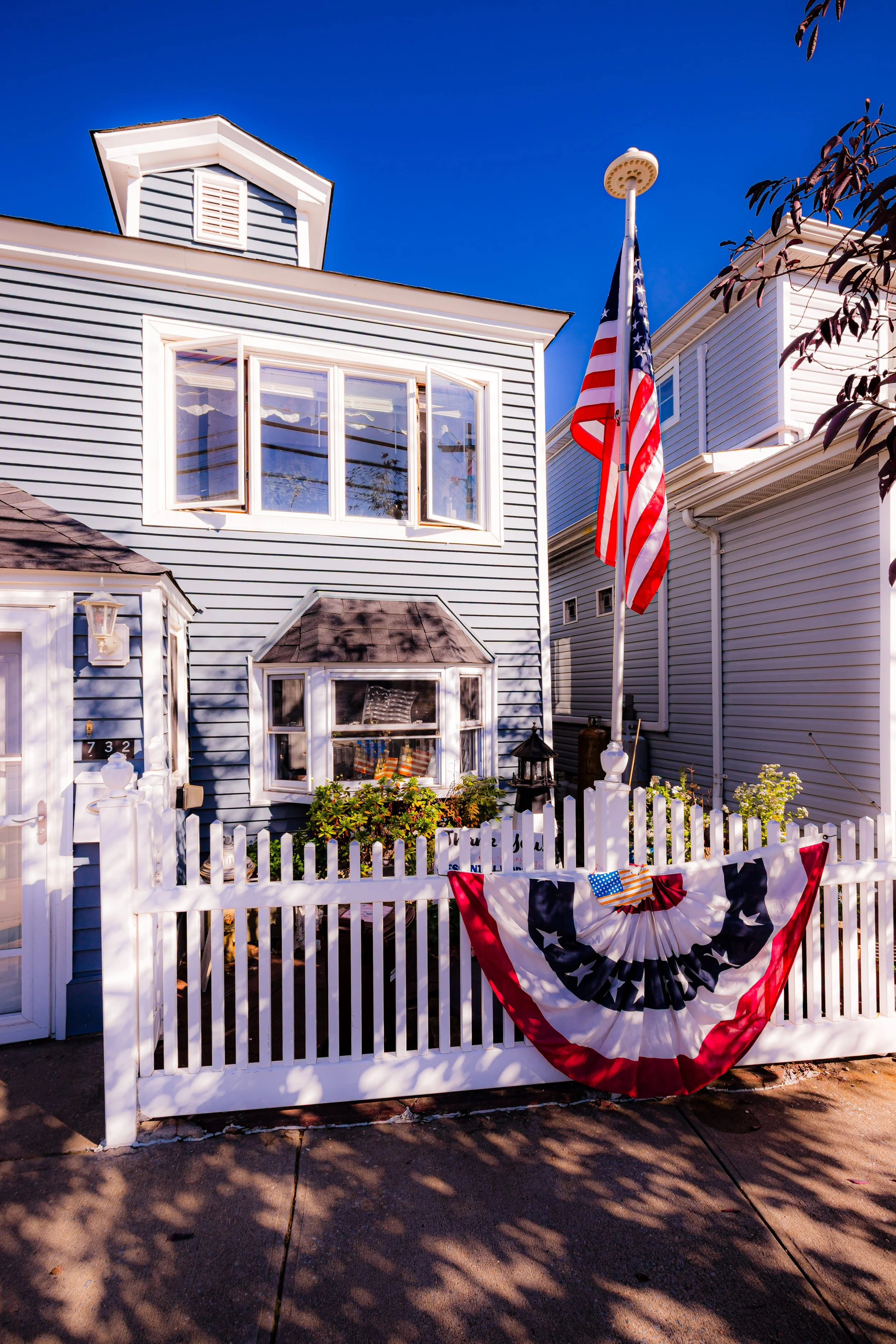 Blue house decorated with American flags and red, white, and blue bunting for a patriotic celebration.