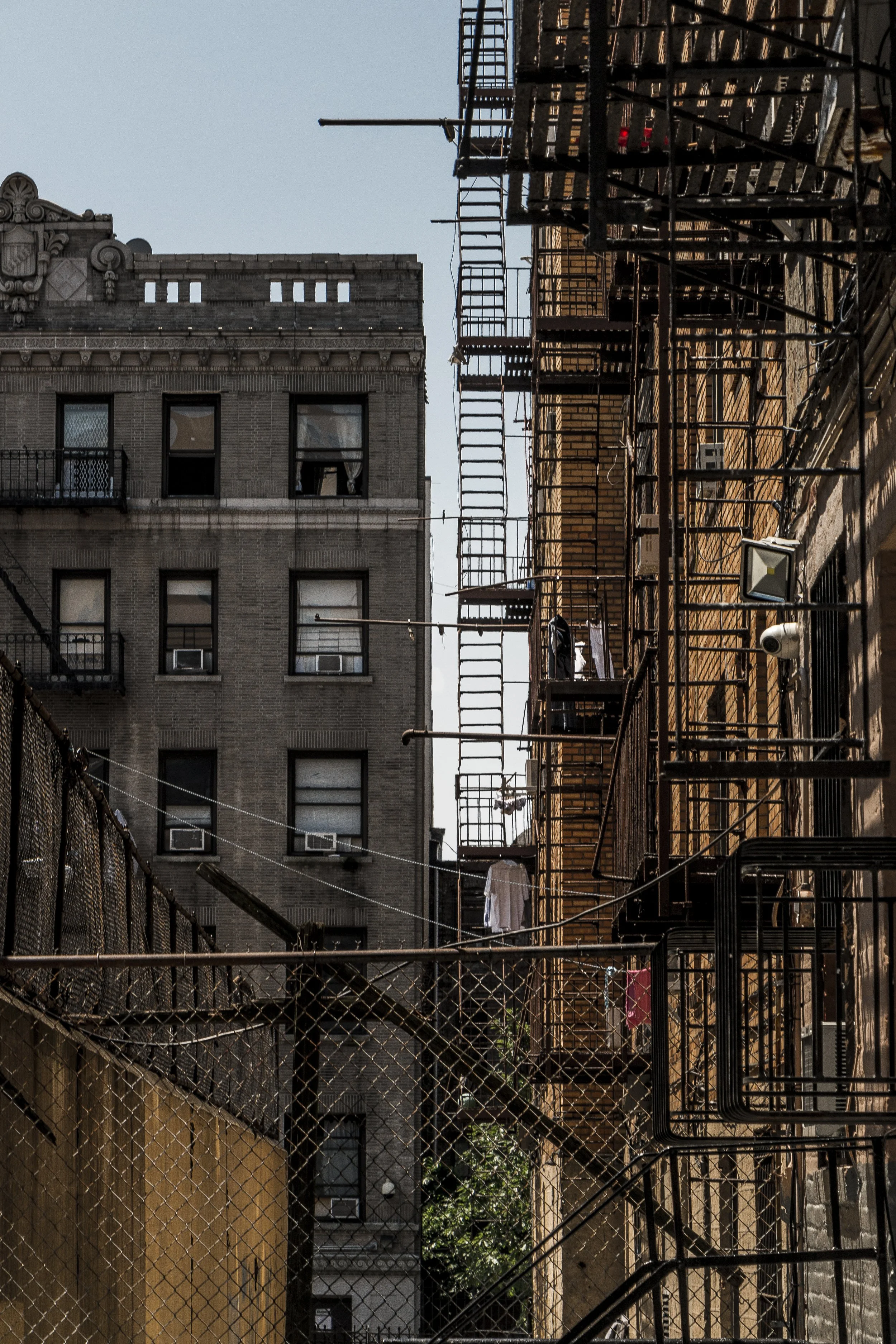 Residential buildings with fire escapes, connecting staircases, and laundry hanging outside in New York City.