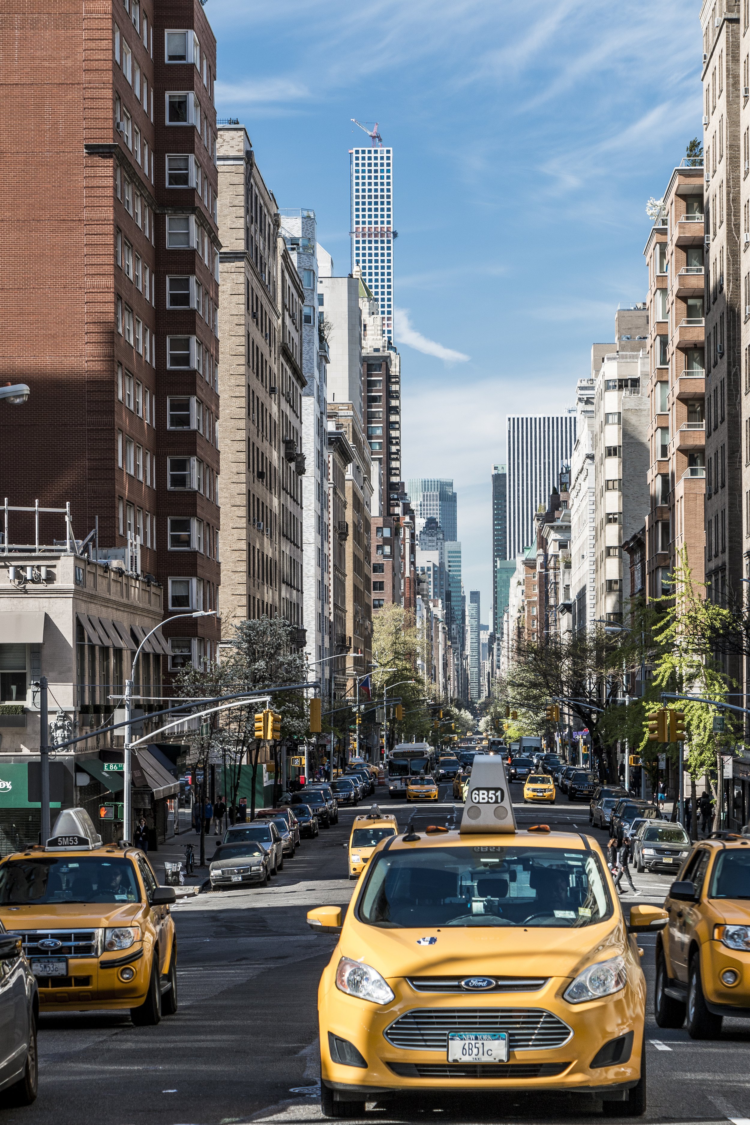 Street scene in New York City with yellow taxis, tall buildings, and a clear blue sky.