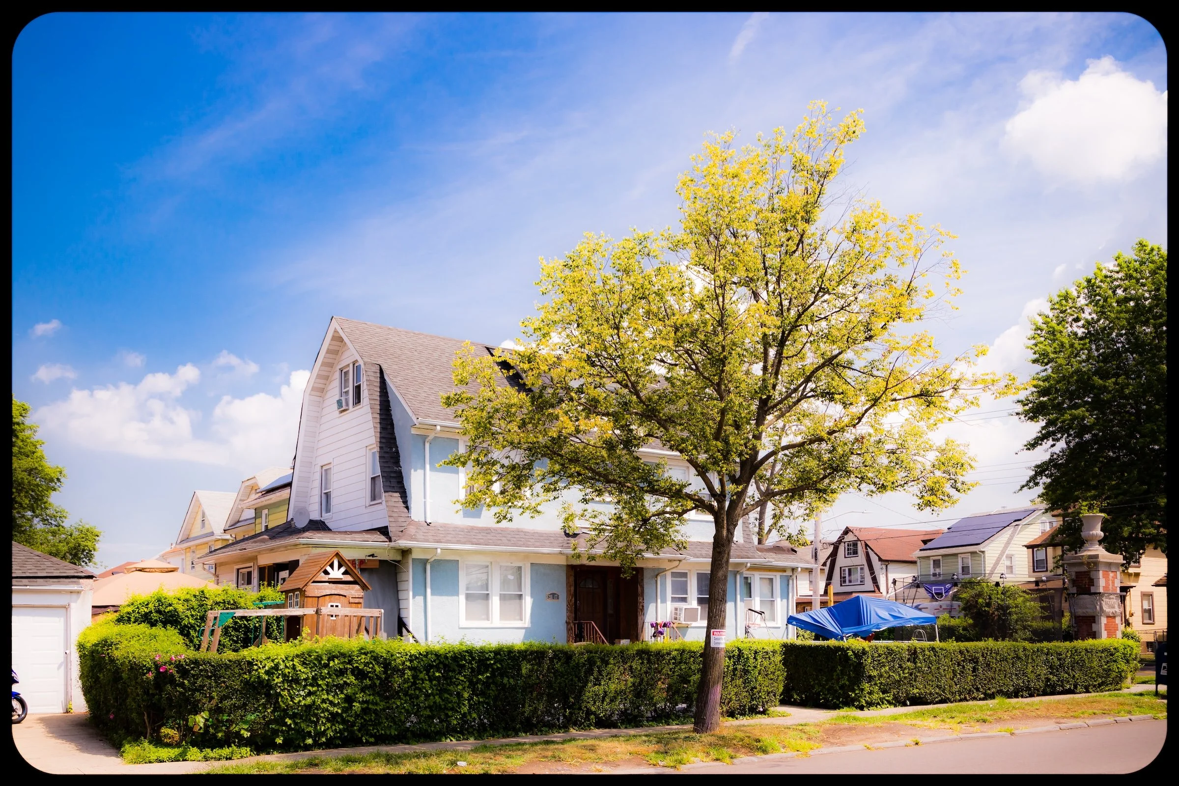 A black and white photo of a person walking through a narrow alleyway at night, with buildings on both sides, graffiti on the wall, and bright light illuminating the background.