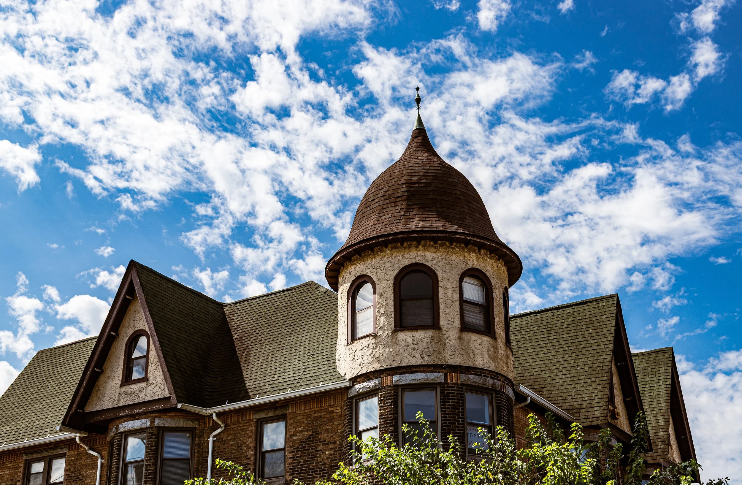 Historic house with a turret and Victorian architecture under a partly cloudy sky.