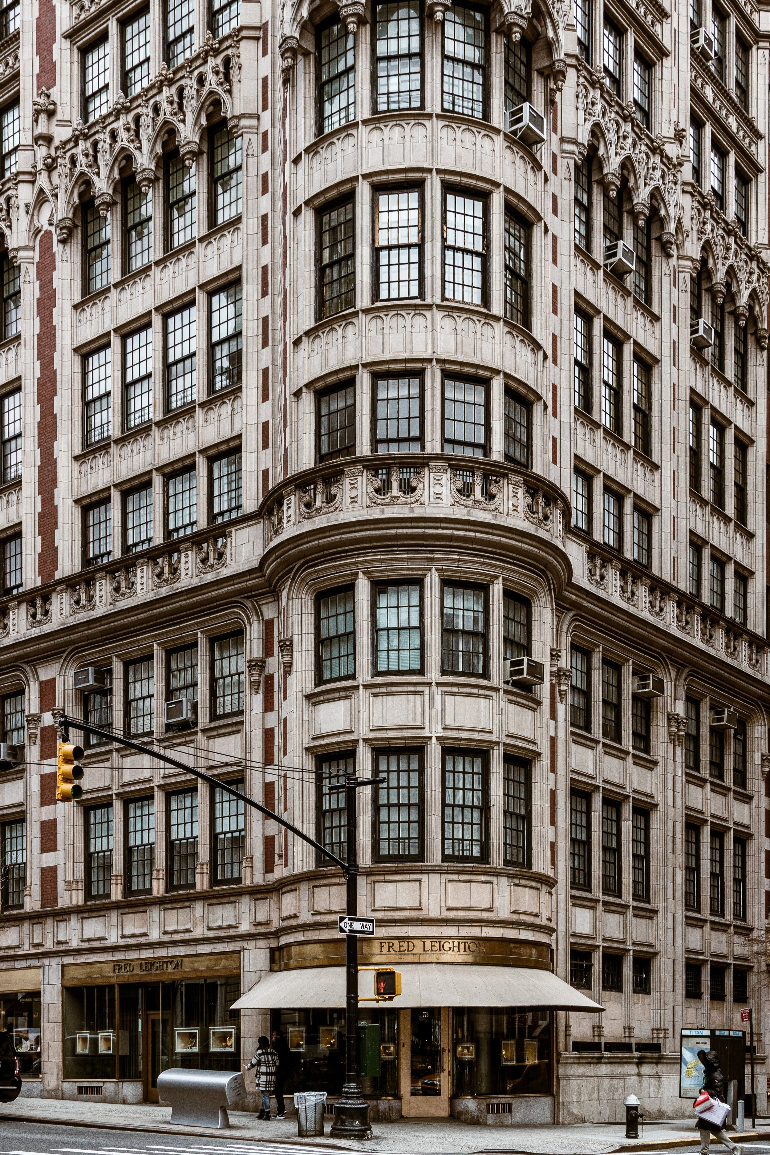 A historic multi-story building with ornate architectural detailing, large windows, and a storefront on the ground level labeled 'Fred Leighton' on a city street corner.