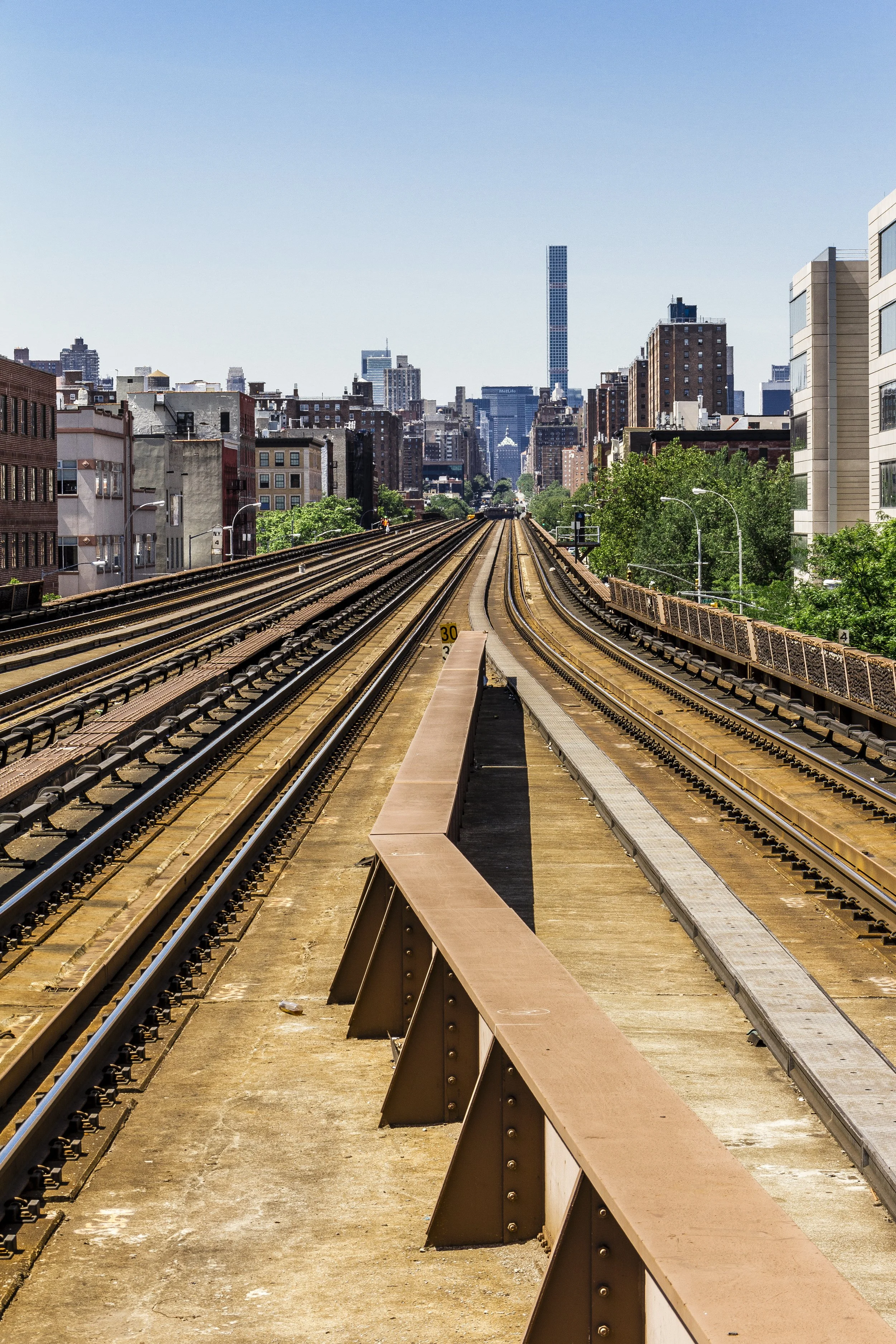 Cityscape with railway tracks and urban buildings under clear blue sky.