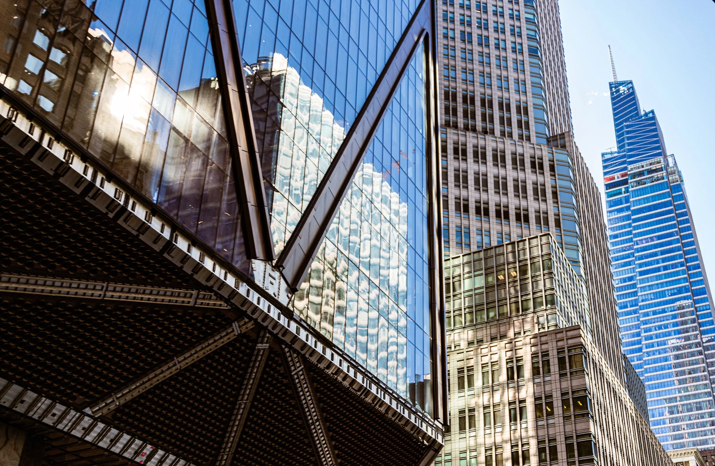 Tall modern glass skyscrapers reflecting the sky and other buildings in an urban city.