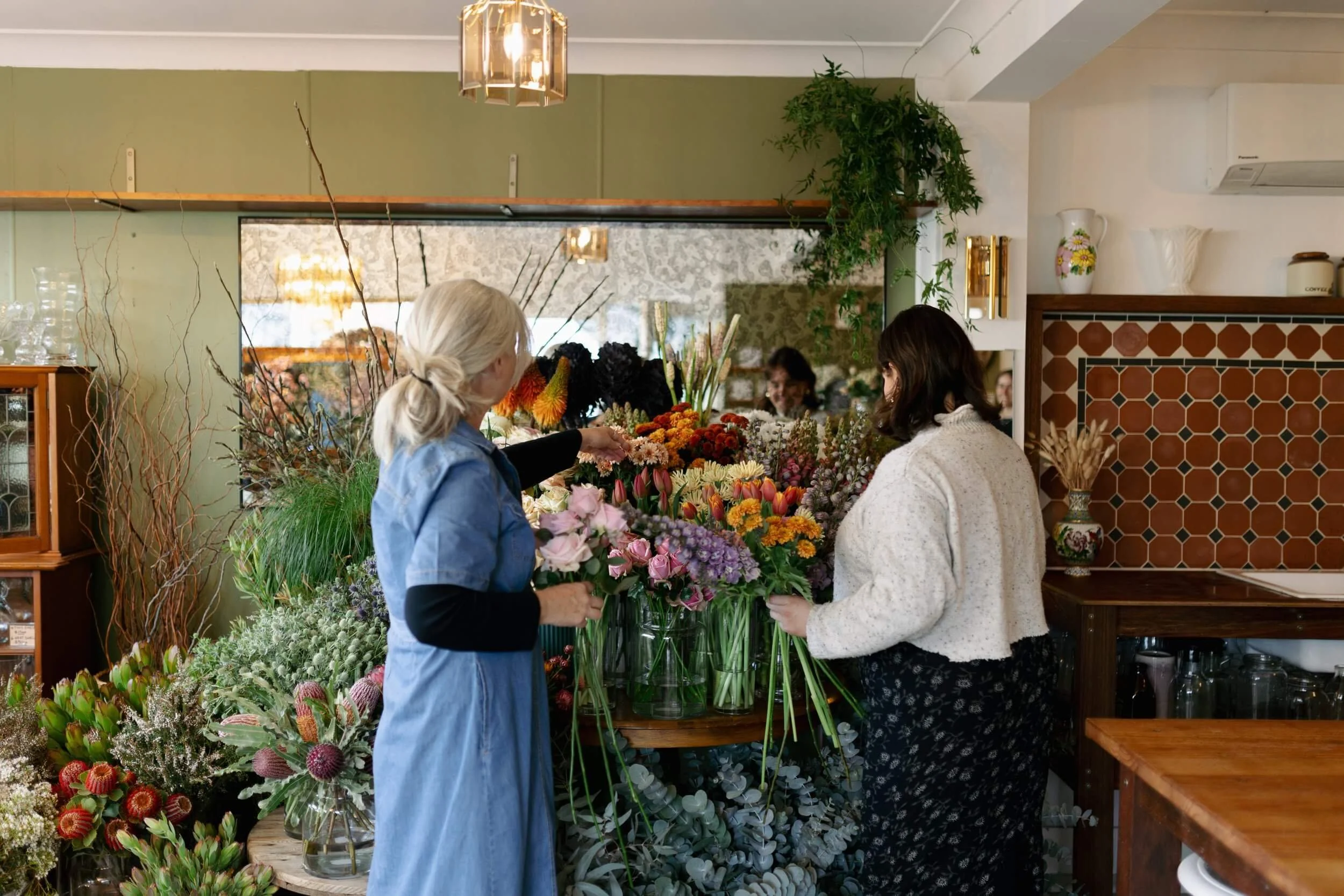 Two women arranging colourful flowers at The Little Garden shop in Lake Macquarie.