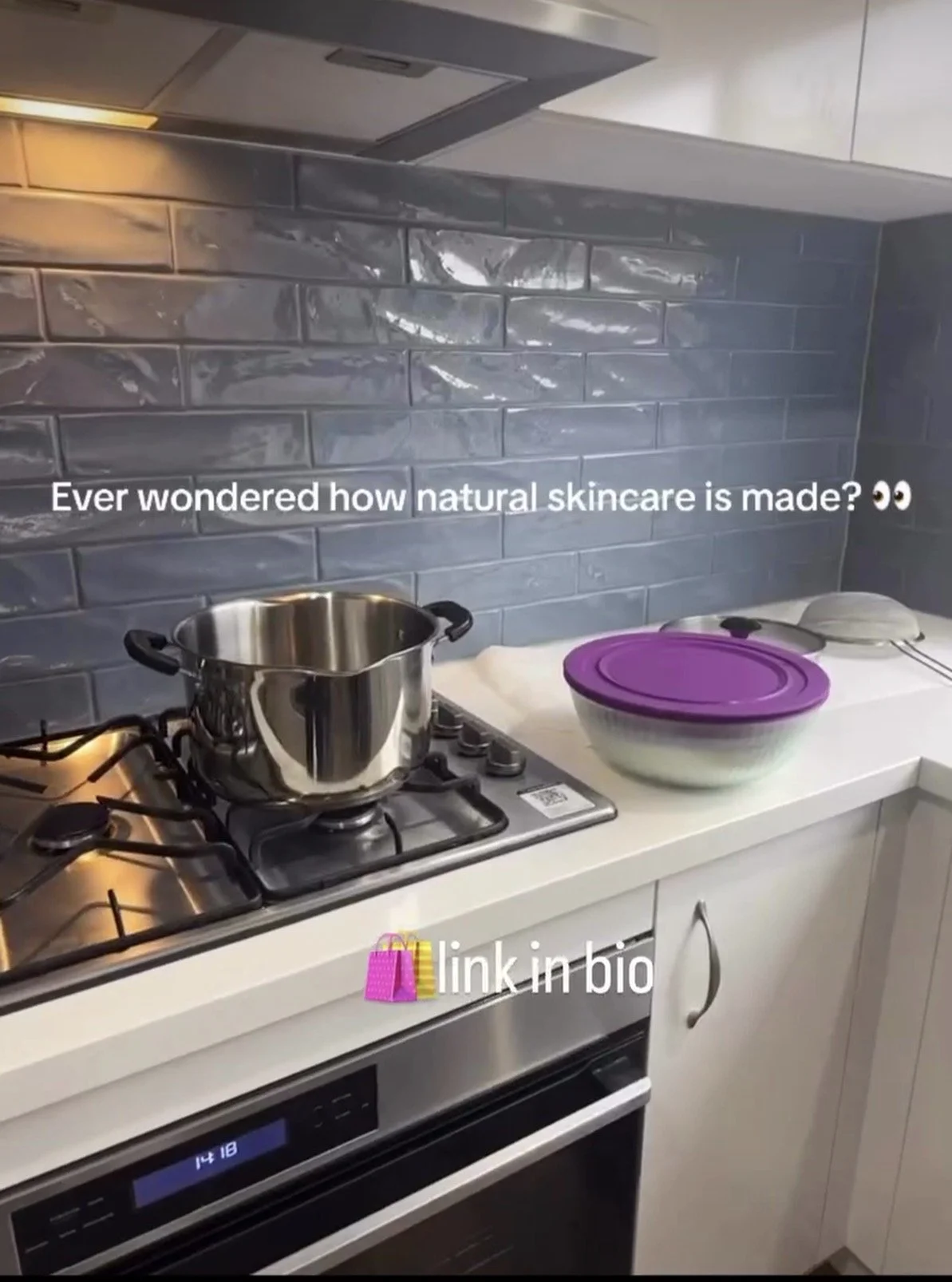 A kitchen countertop with a stainless steel pot on a stove, a purple-lidded bowl, and a stack of other bowls or containers, with a gray tiled backsplash.