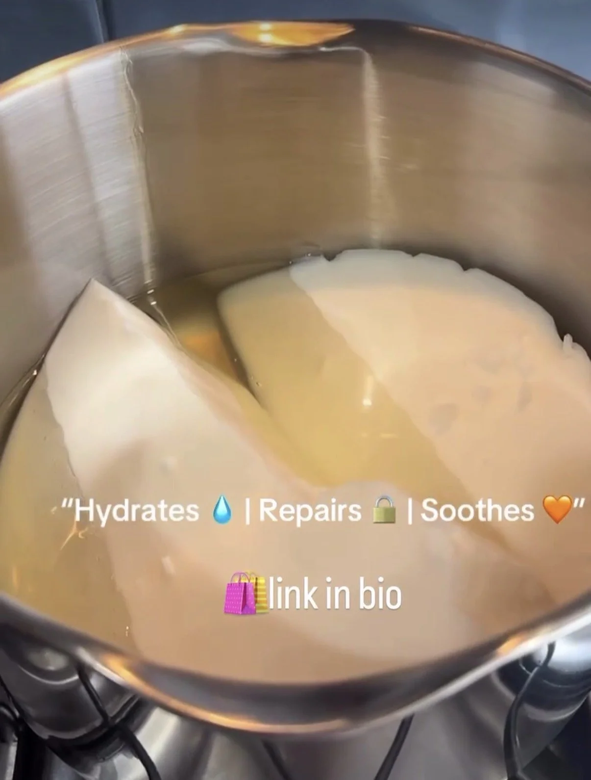 A metal pot with shea butter melting inside on a stove.