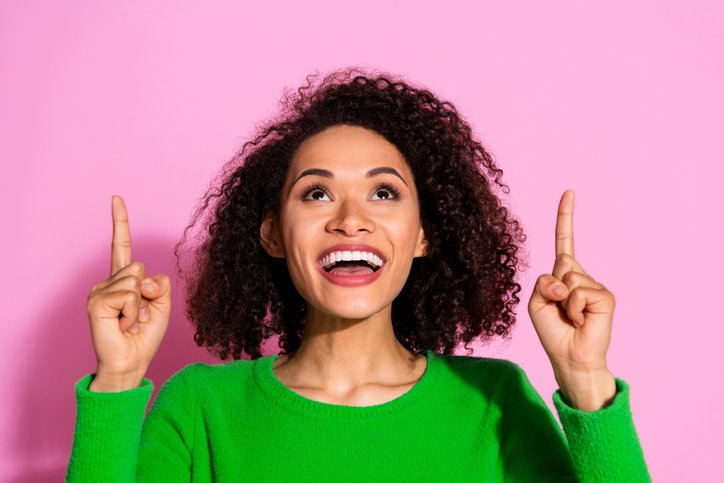 Smiling woman pointing upwards to illustrate managing up and influencing your boss effectively