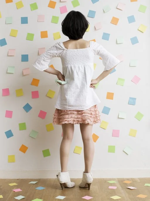 Woman inspecting post it notes on a wall to illustrate volume of ideas