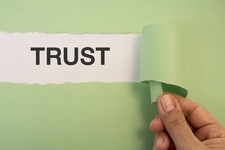 Torn paper reading Trust representing trusting your instincts at work