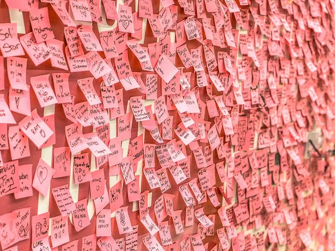 Wall filled with post it notes illustrating the challenge of turning ideas, plans and competing priorities into progress.