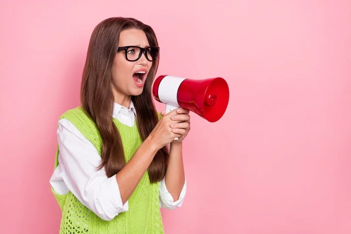 Business woman speaking through a megaphone to illustrate speaking up and managing up effectively