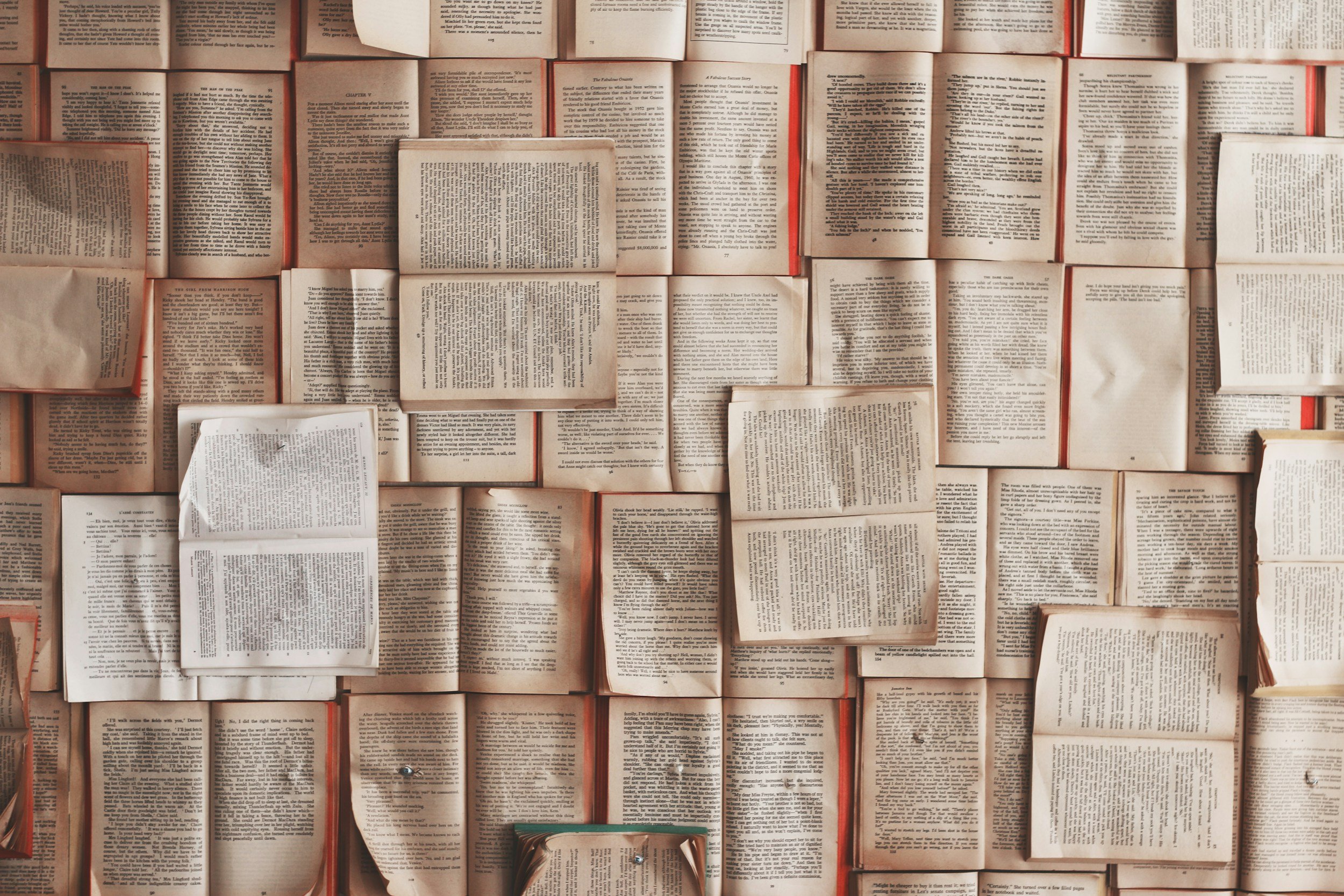 A collection of open books and newspapers laid out on a surface, displaying pages filled with printed text.