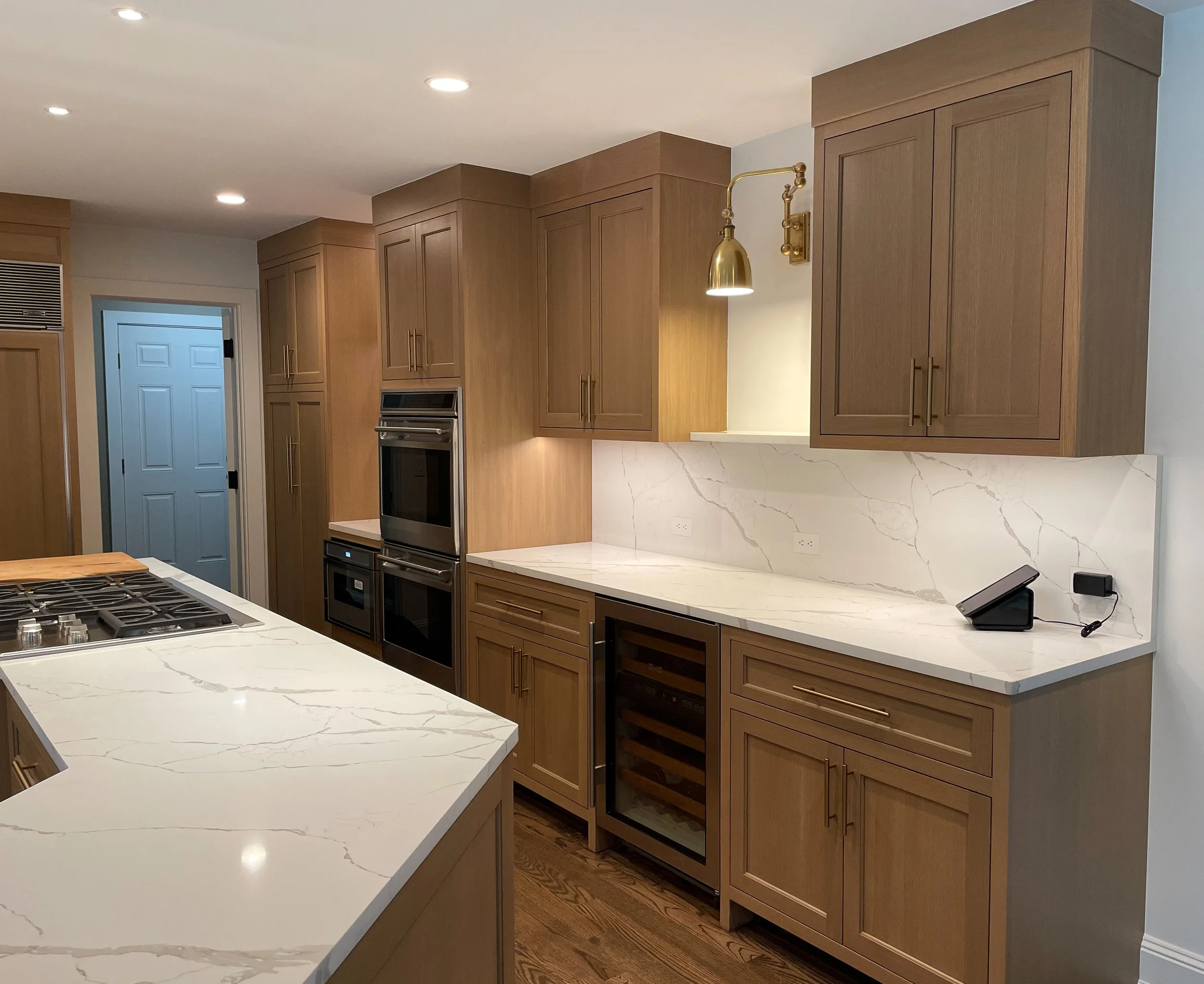 Inset white oak kitchen with quartz countertops and brass hardware 